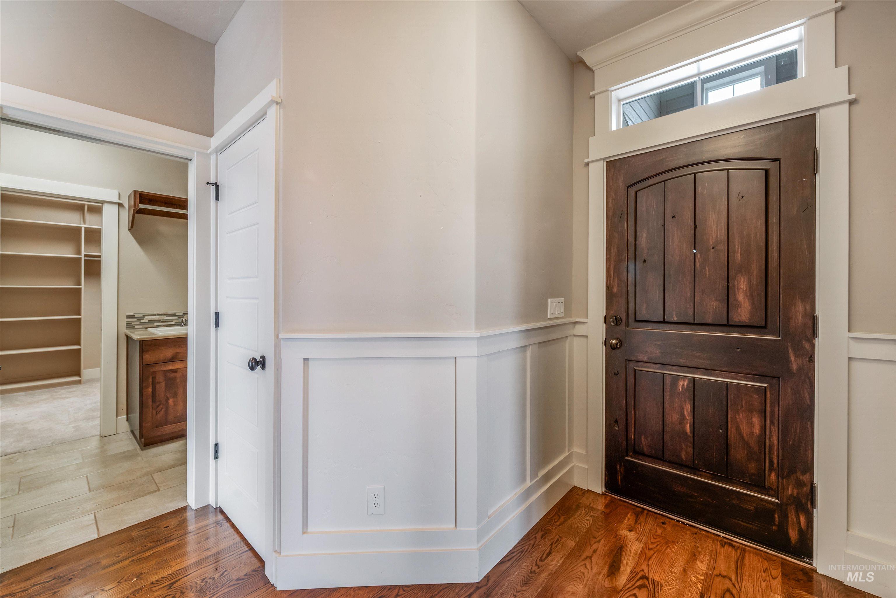 Foyer featuring wood finished floors, a wainscoted wall, and a decorative wall