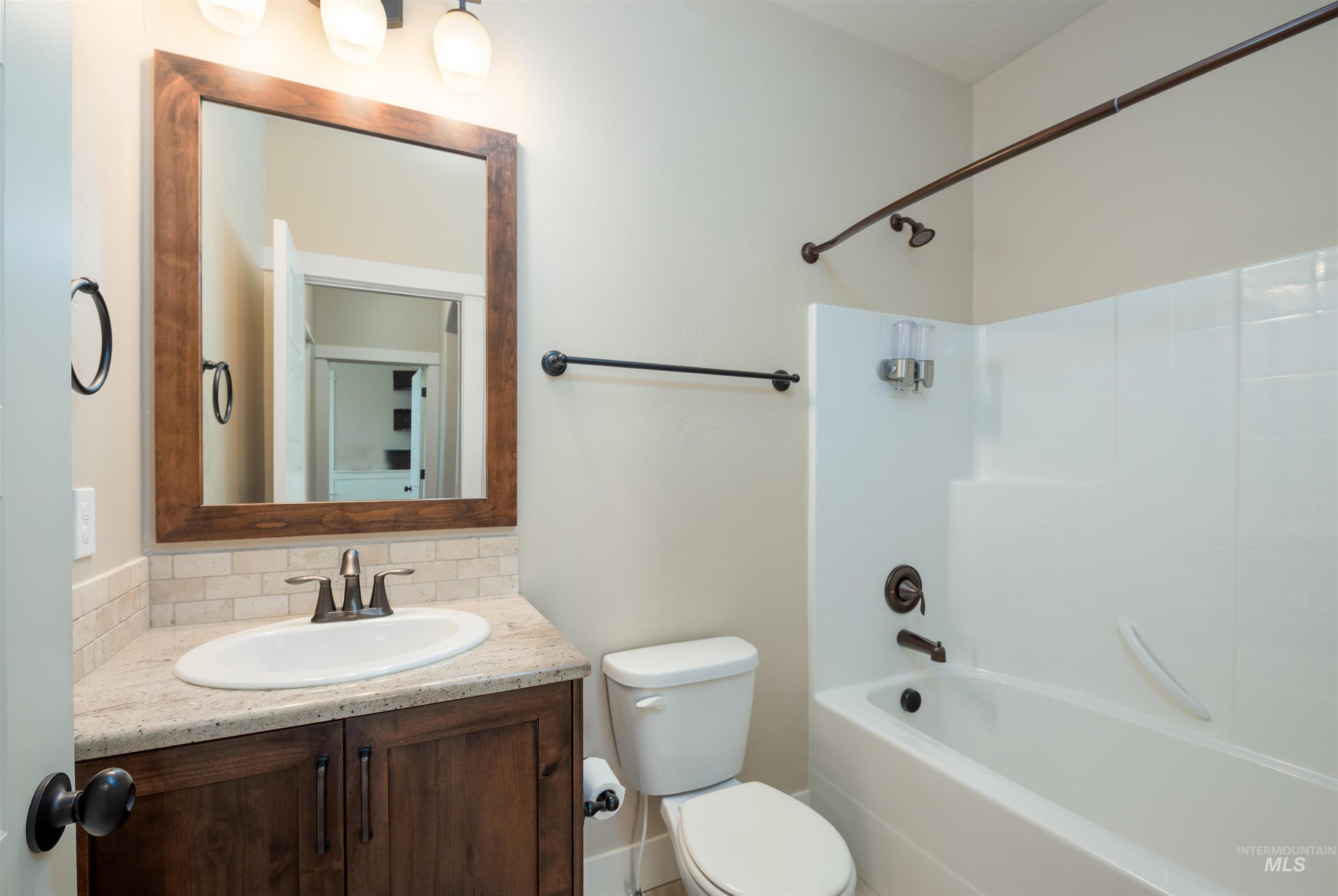 Full bath featuring vanity, shower / bathtub combination, and tasteful backsplash