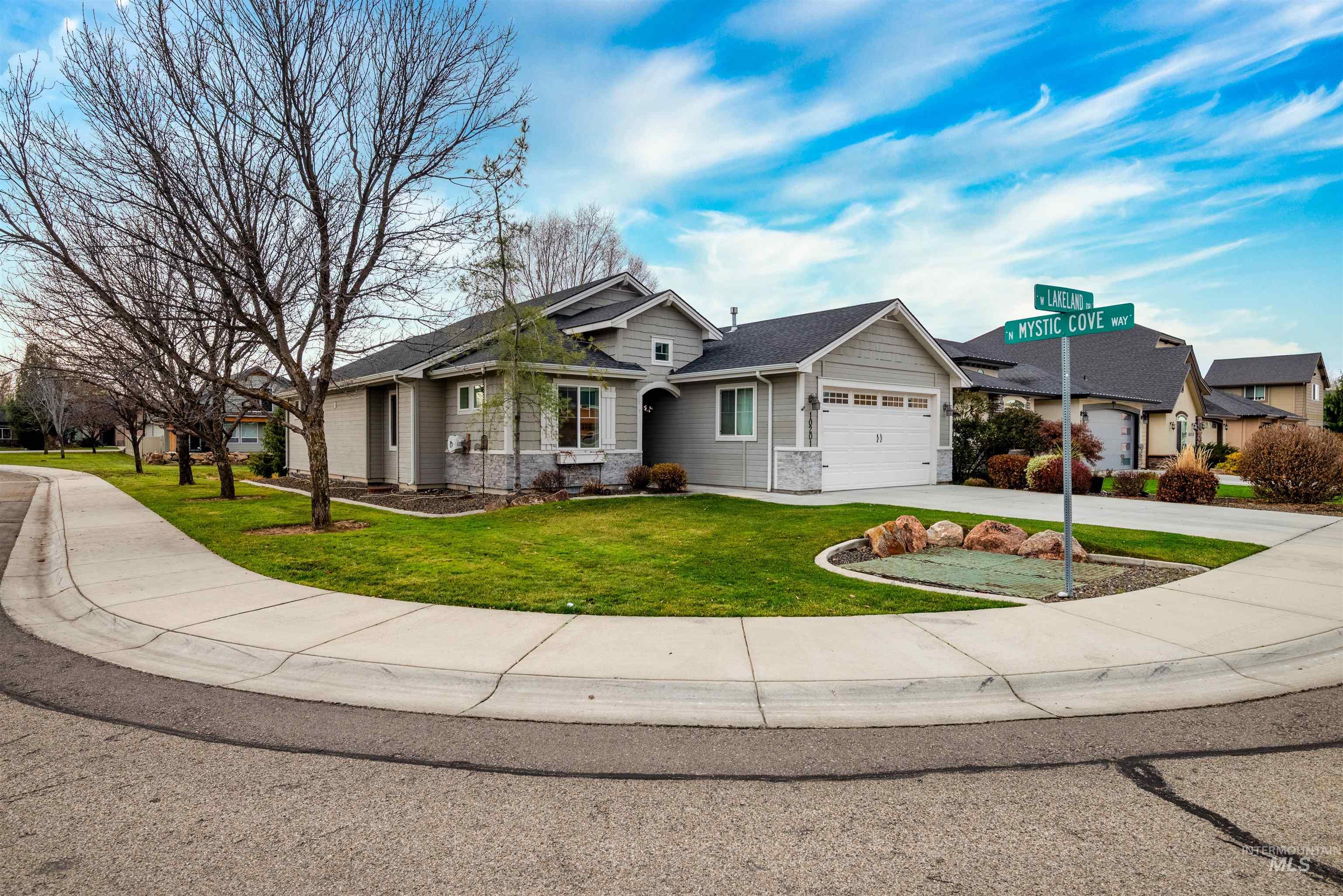 View of front of property with a front yard, concrete driveway, stone siding, a garage, and a residential view