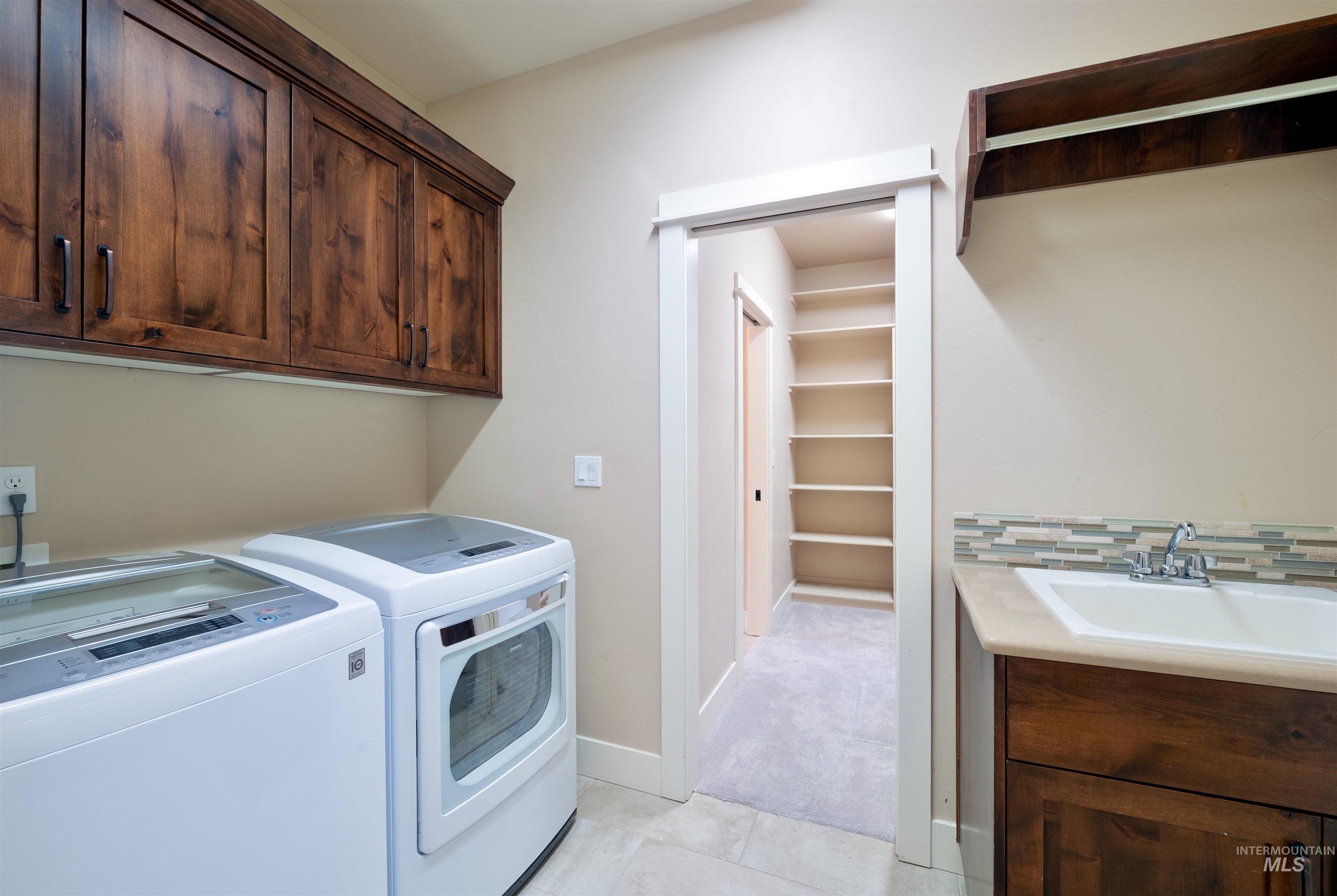 Laundry area with cabinet space, washing machine and clothes dryer, and light tile patterned floors