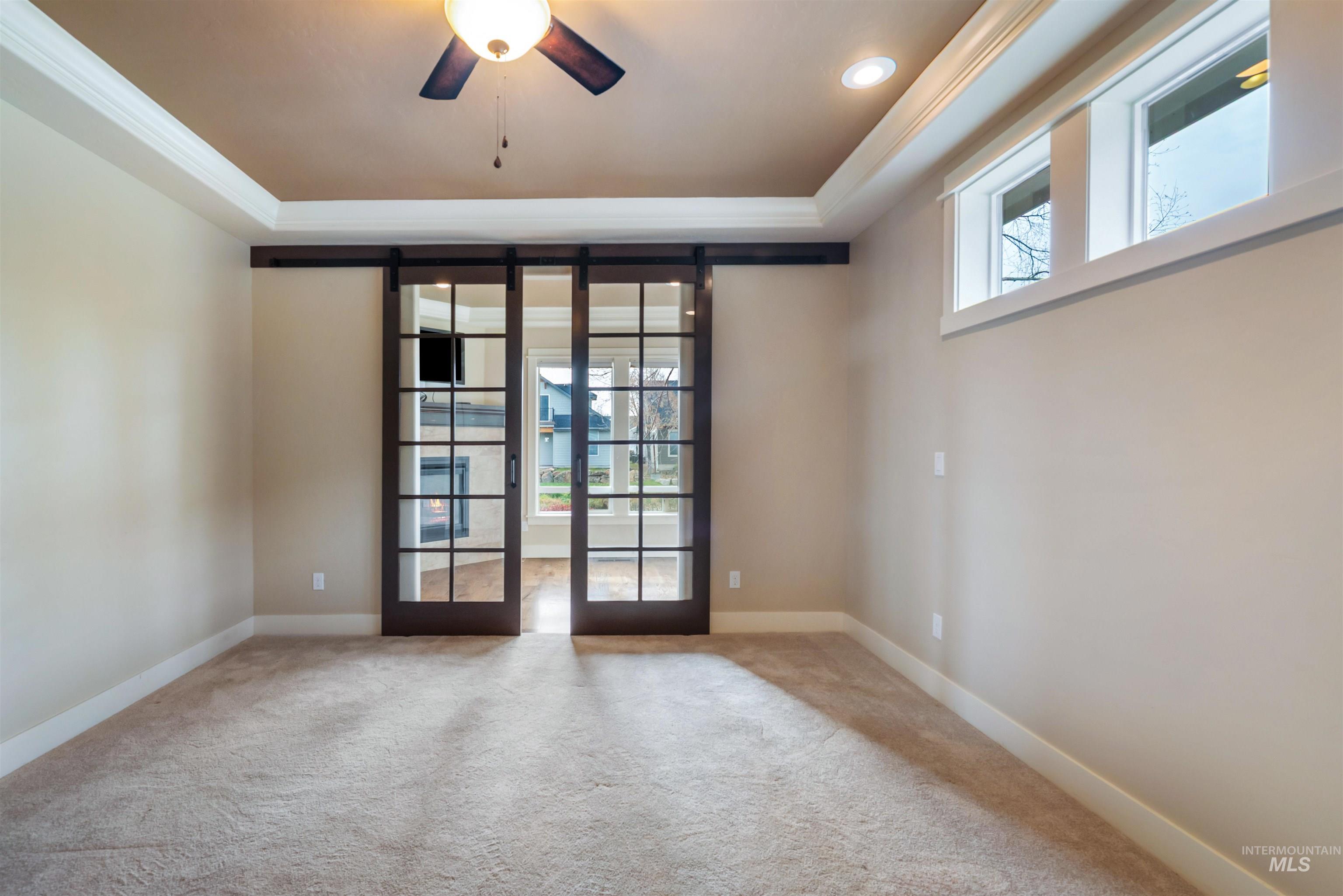 Unfurnished room featuring a tray ceiling, crown molding, ceiling fan, and carpet floors