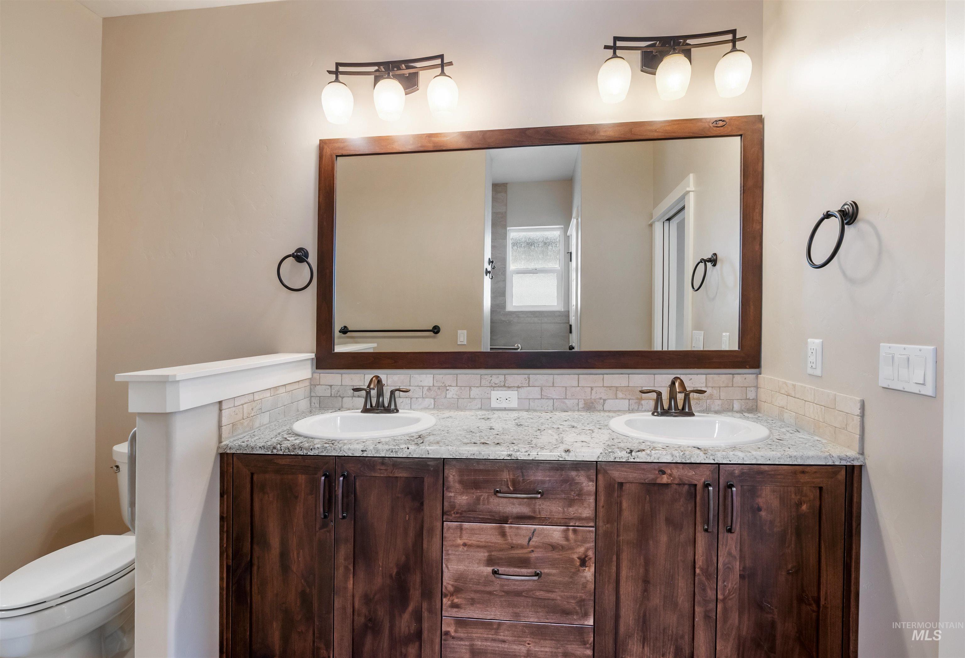 Bathroom featuring double vanity and backsplash