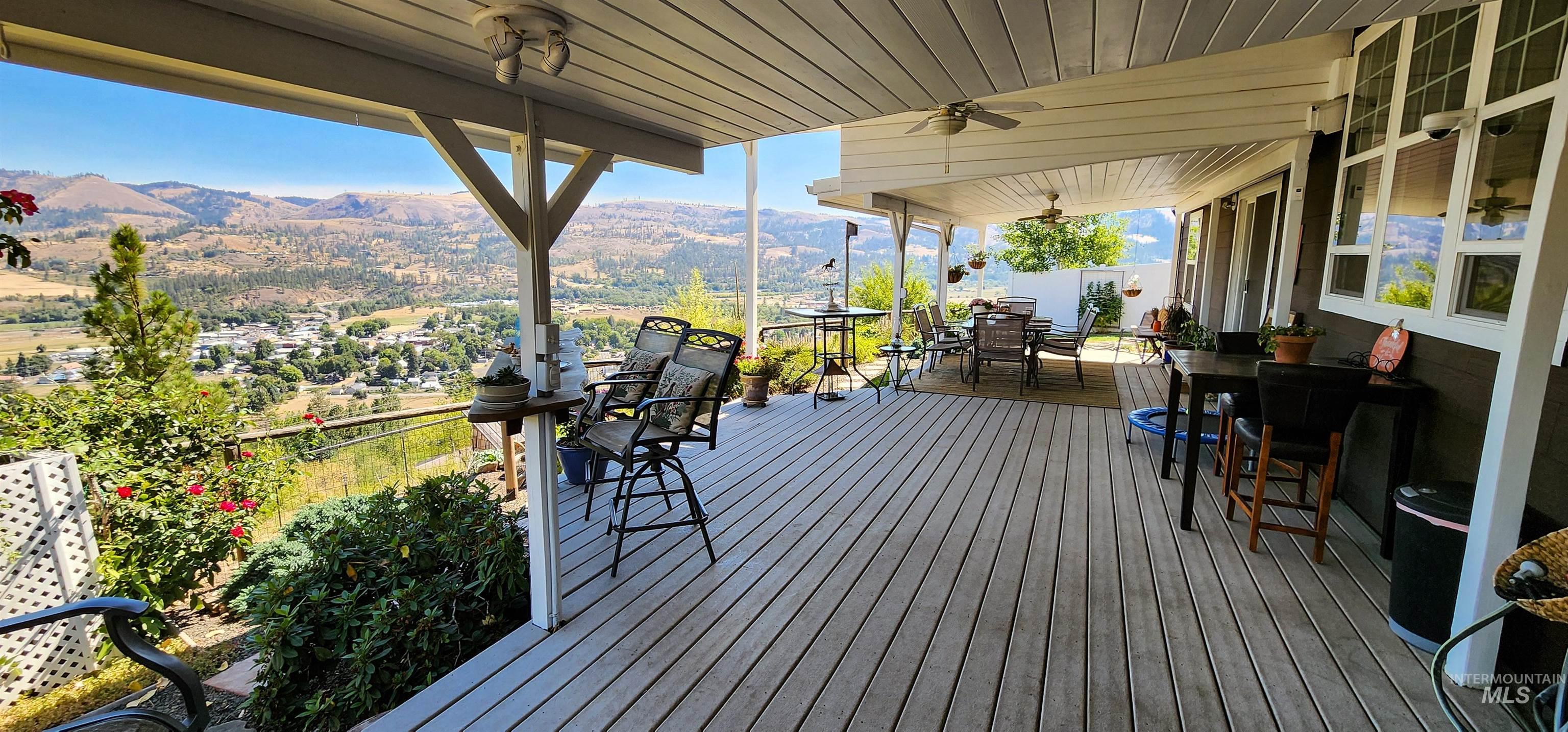 Wooden terrace featuring a mountain view, outdoor dining area, and a ceiling fan