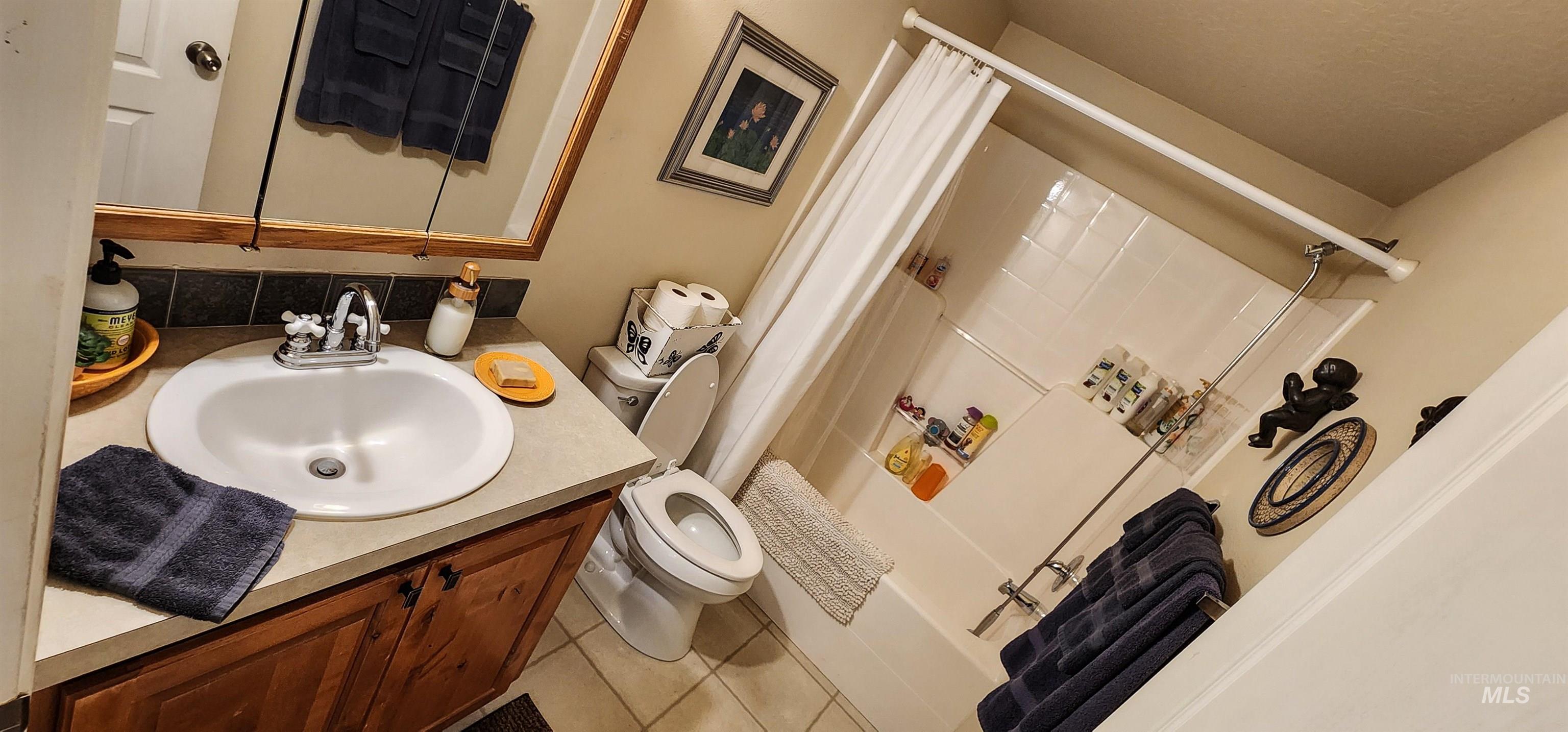 Full bath featuring shower / bathtub combination with curtain, vanity, and tile patterned floors