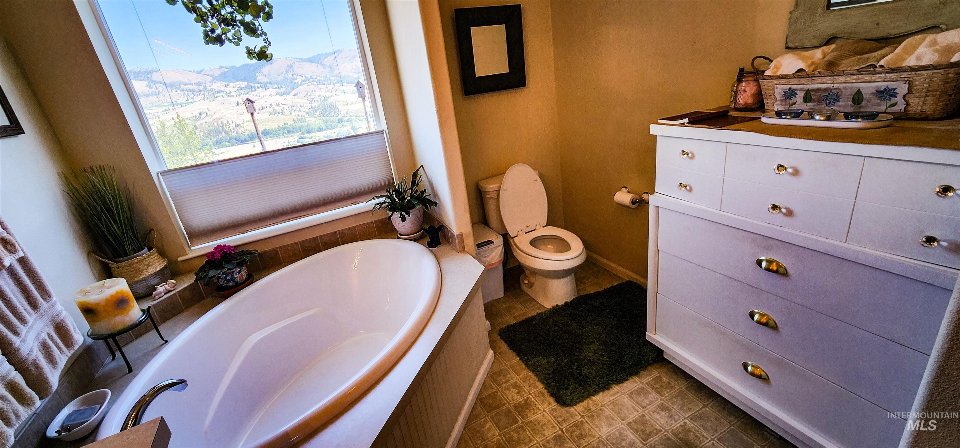 Bathroom with a garden tub, vanity, and dark tile patterned floors