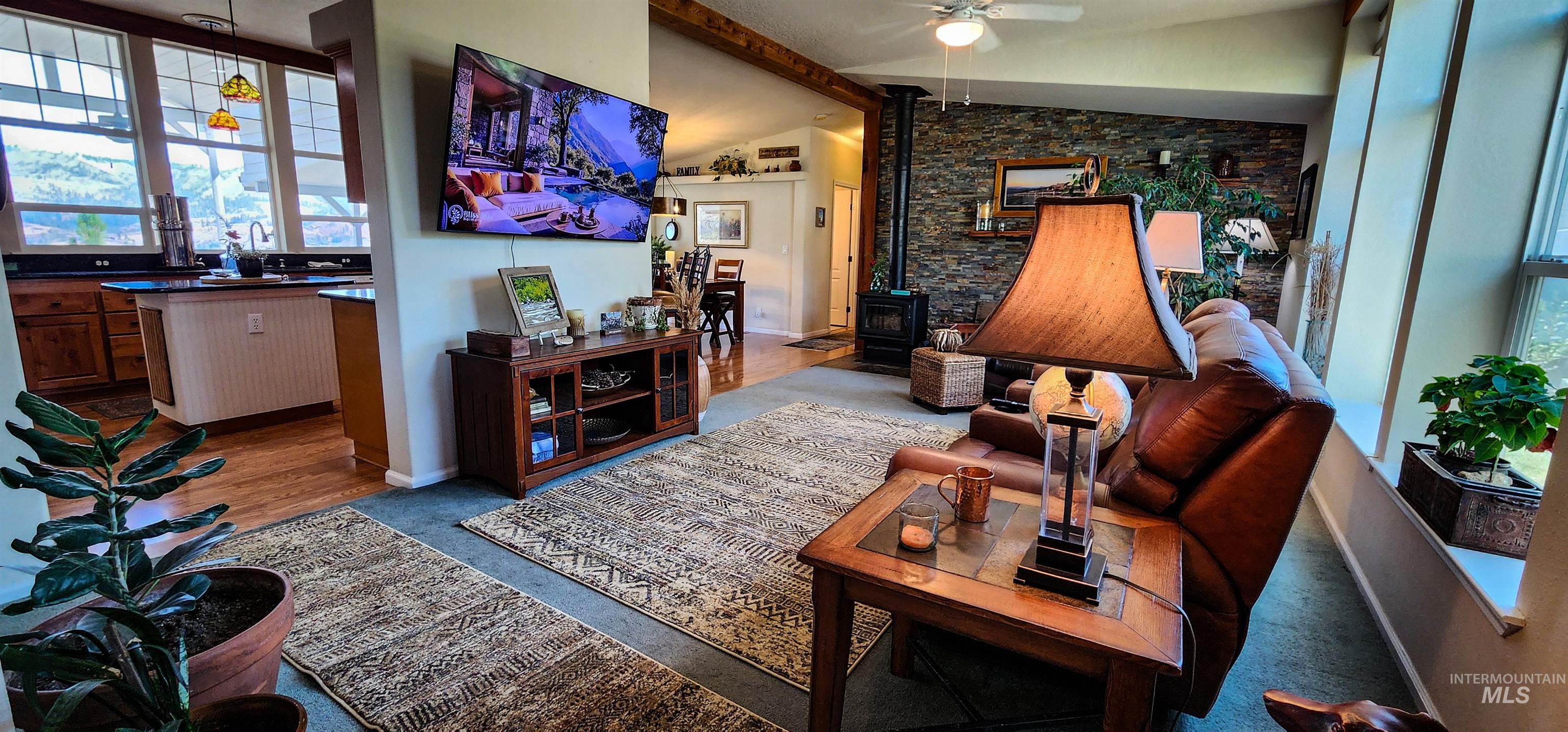 Living area featuring a wood stove, ceiling fan, and wood finished floors
