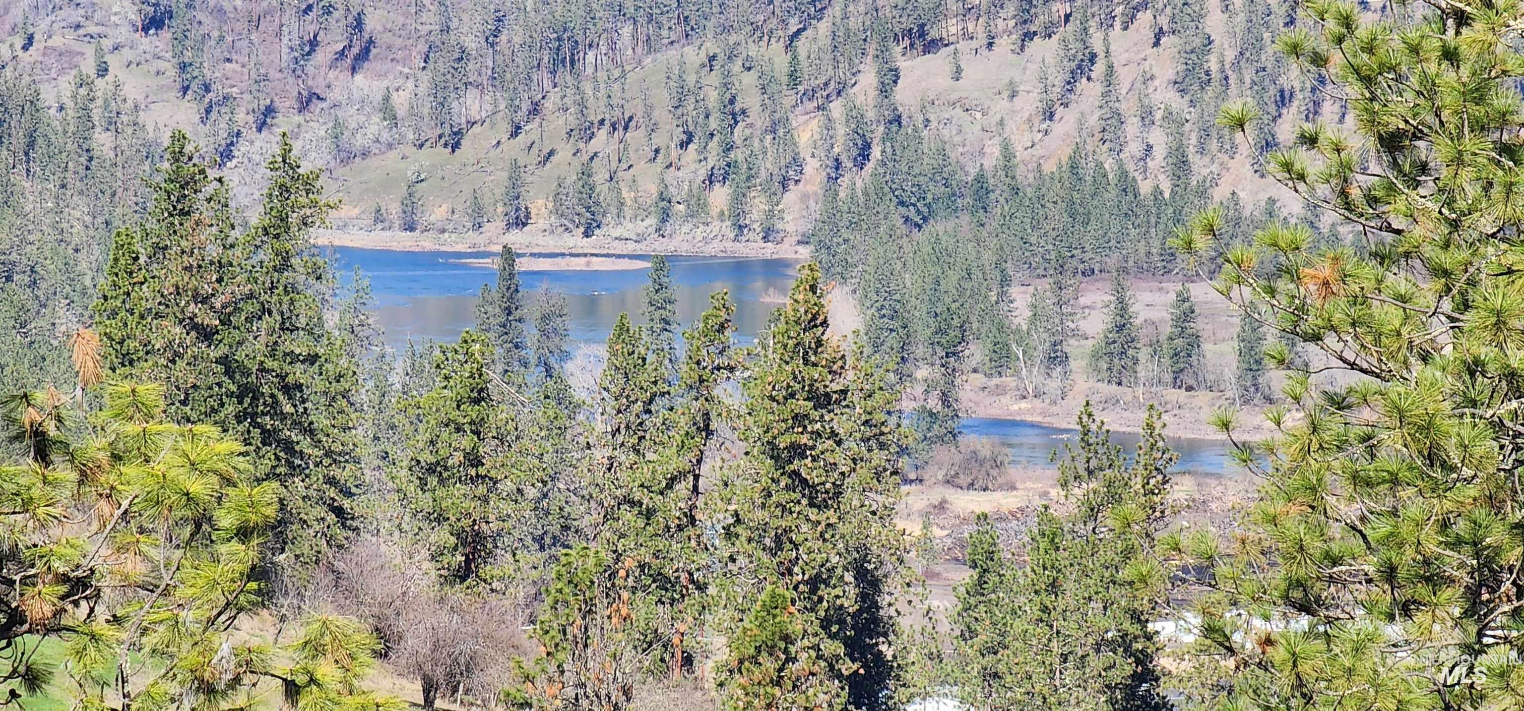 View of mountain backdrop with a nearby body of water and a heavily wooded area