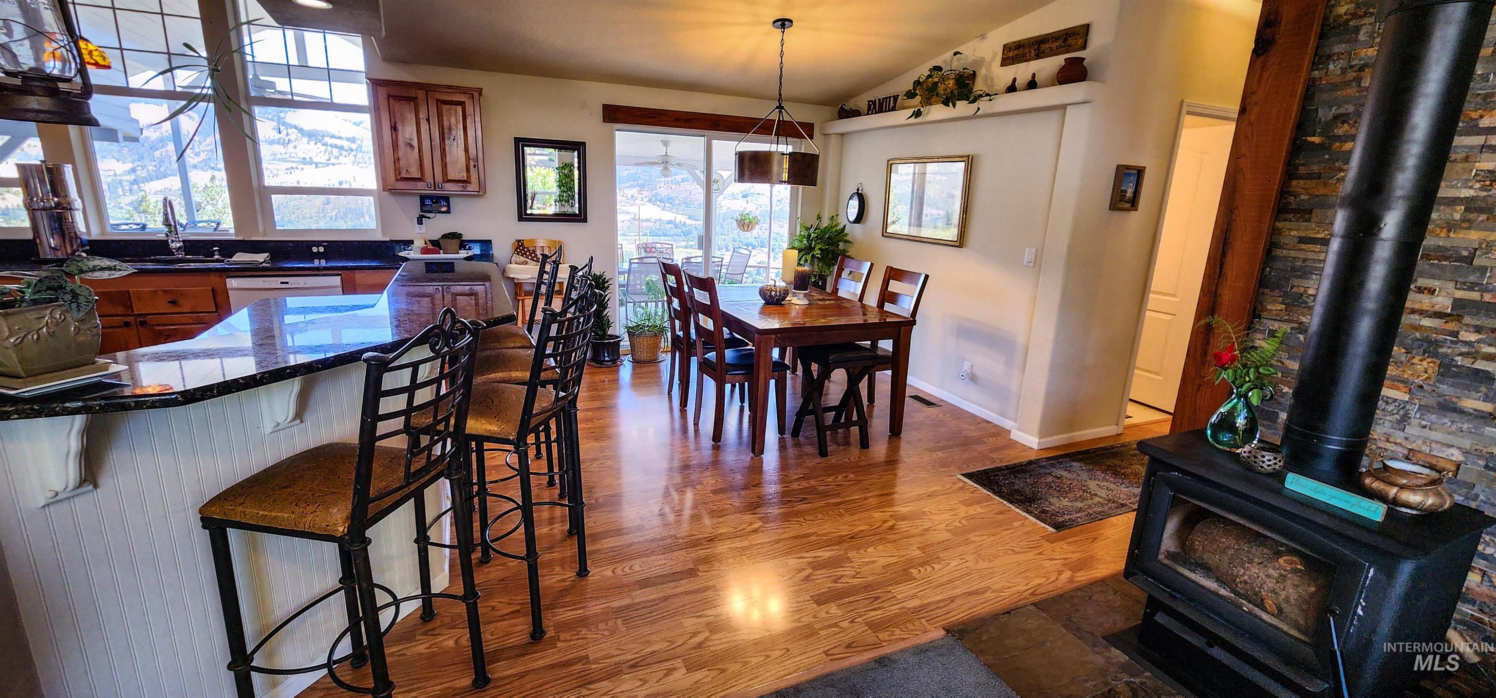 Dining area featuring lofted ceiling, dark wood-type flooring, and a wood stove