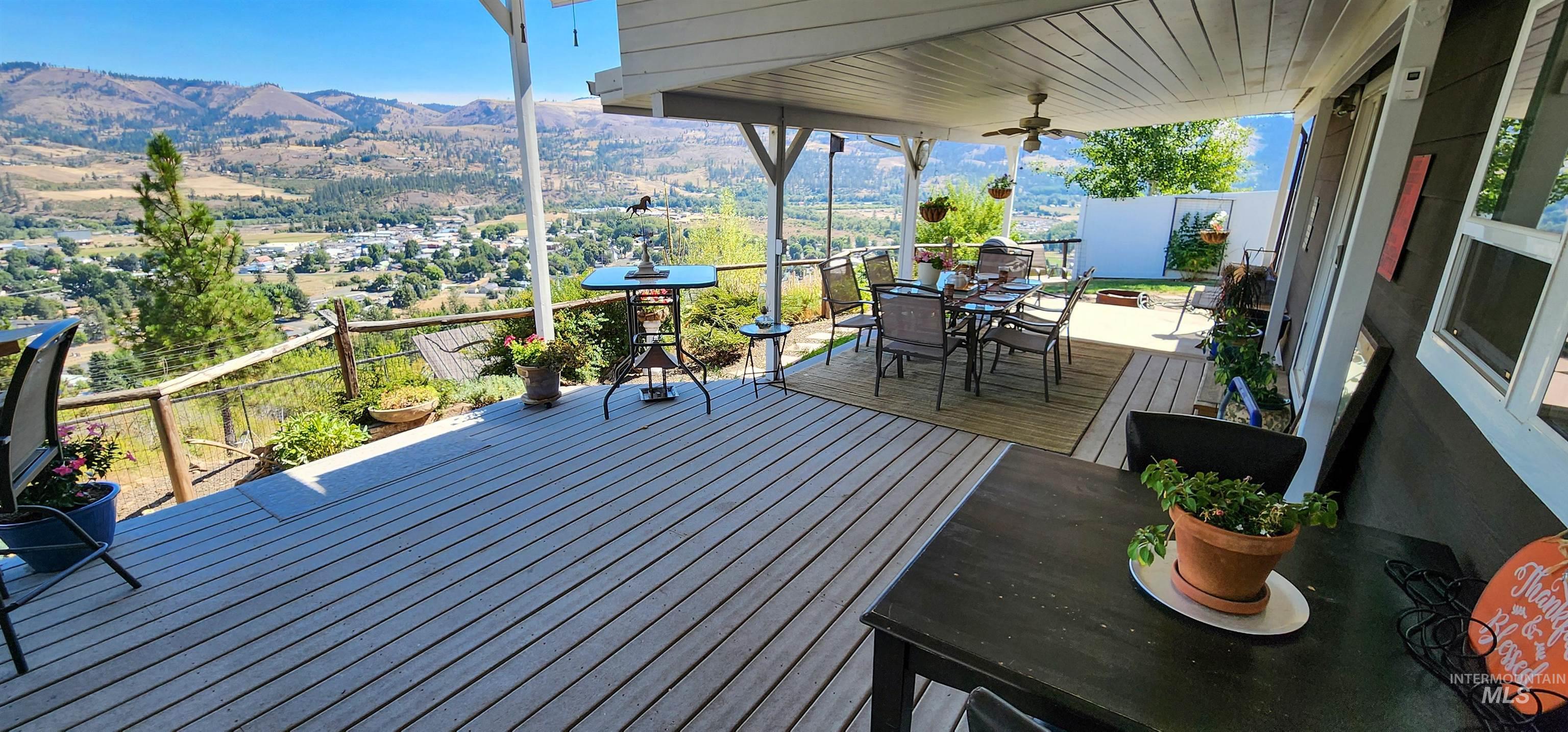 Deck with outdoor dining area, a mountain view, and a ceiling fan