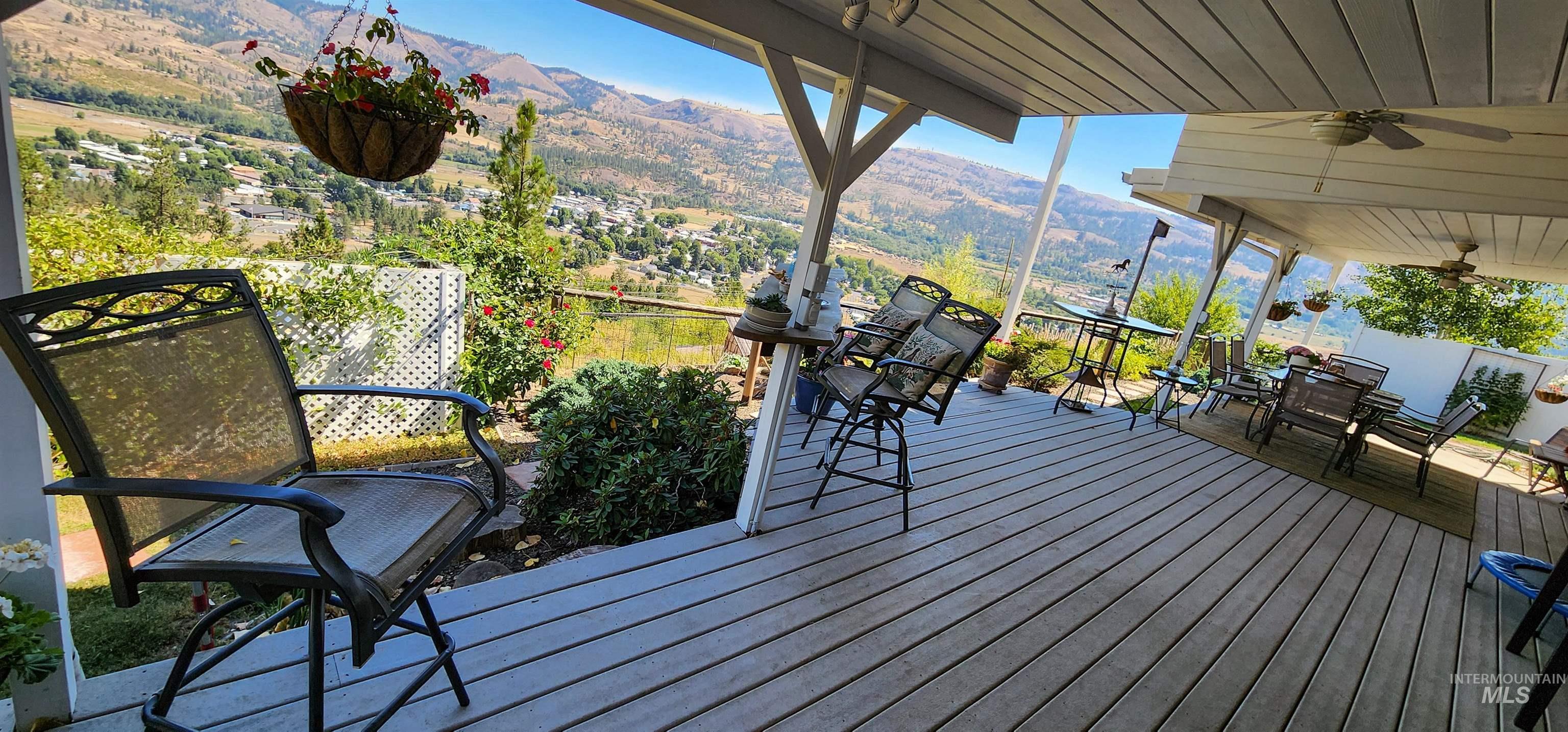 Wooden terrace with a mountain view, ceiling fan, and outdoor dining space