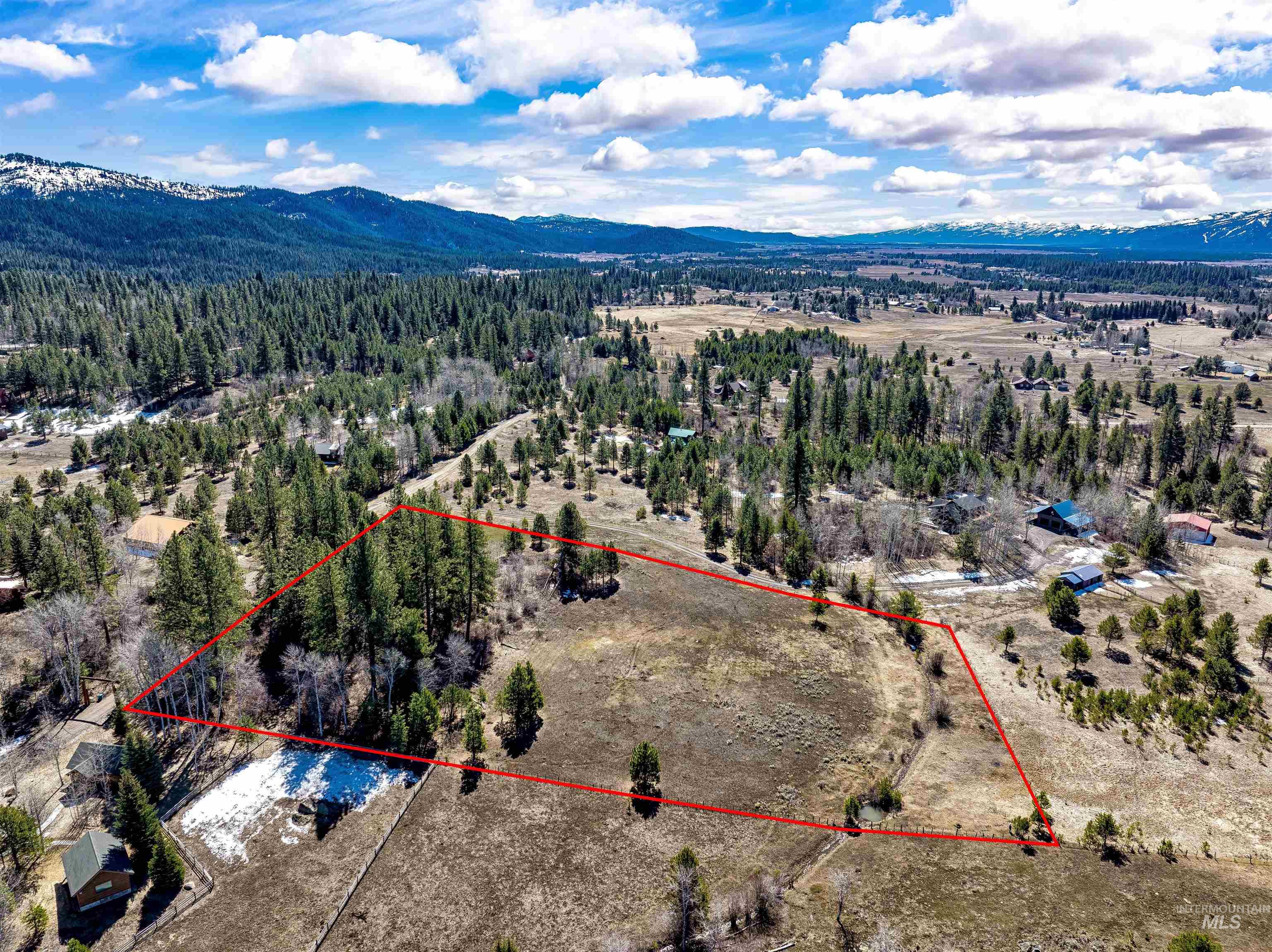 Aerial view of property and surrounding area with a mountainous background and property parcel outlined