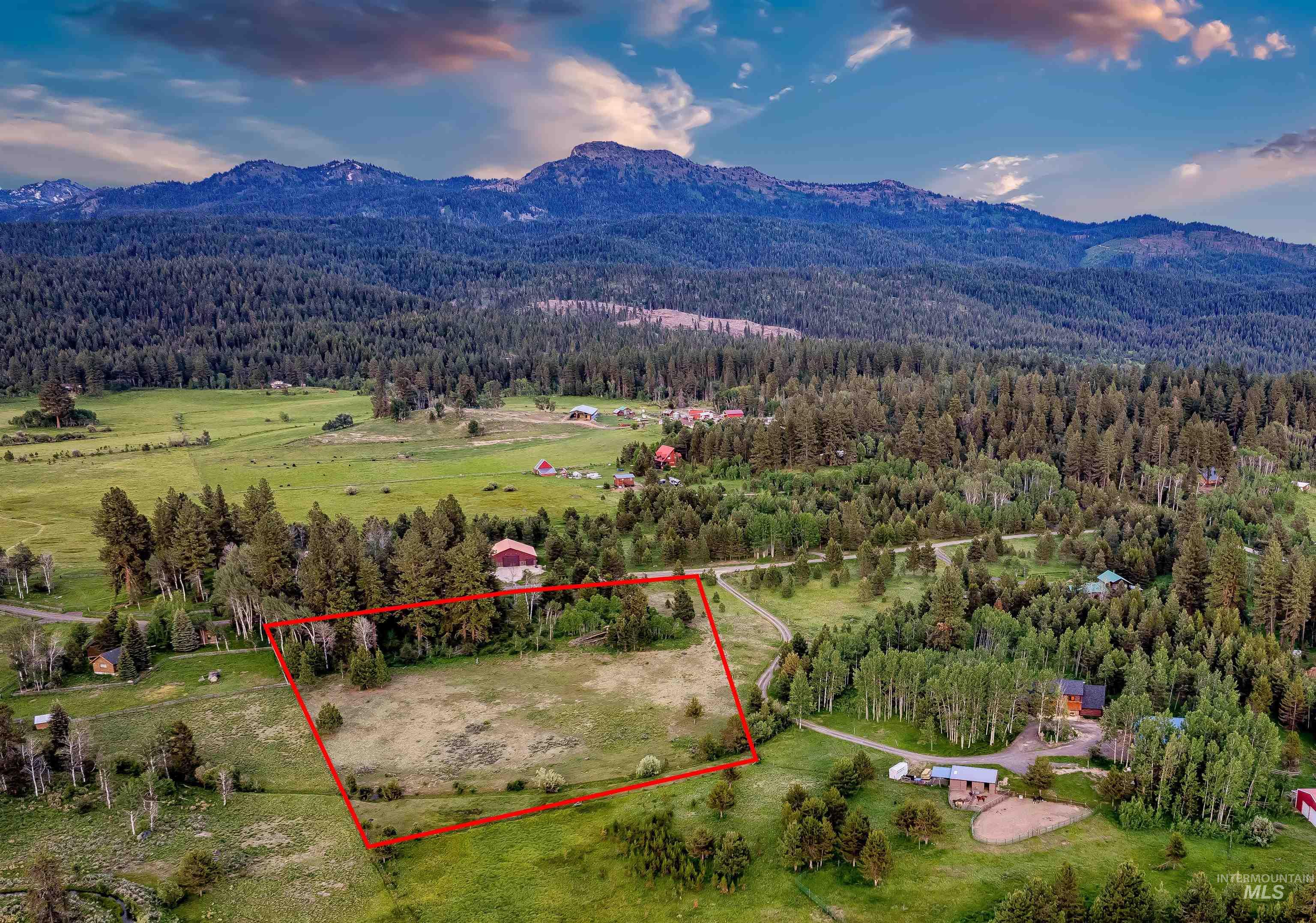 Aerial overview of property's location with property parcel outlined and a mountainous background