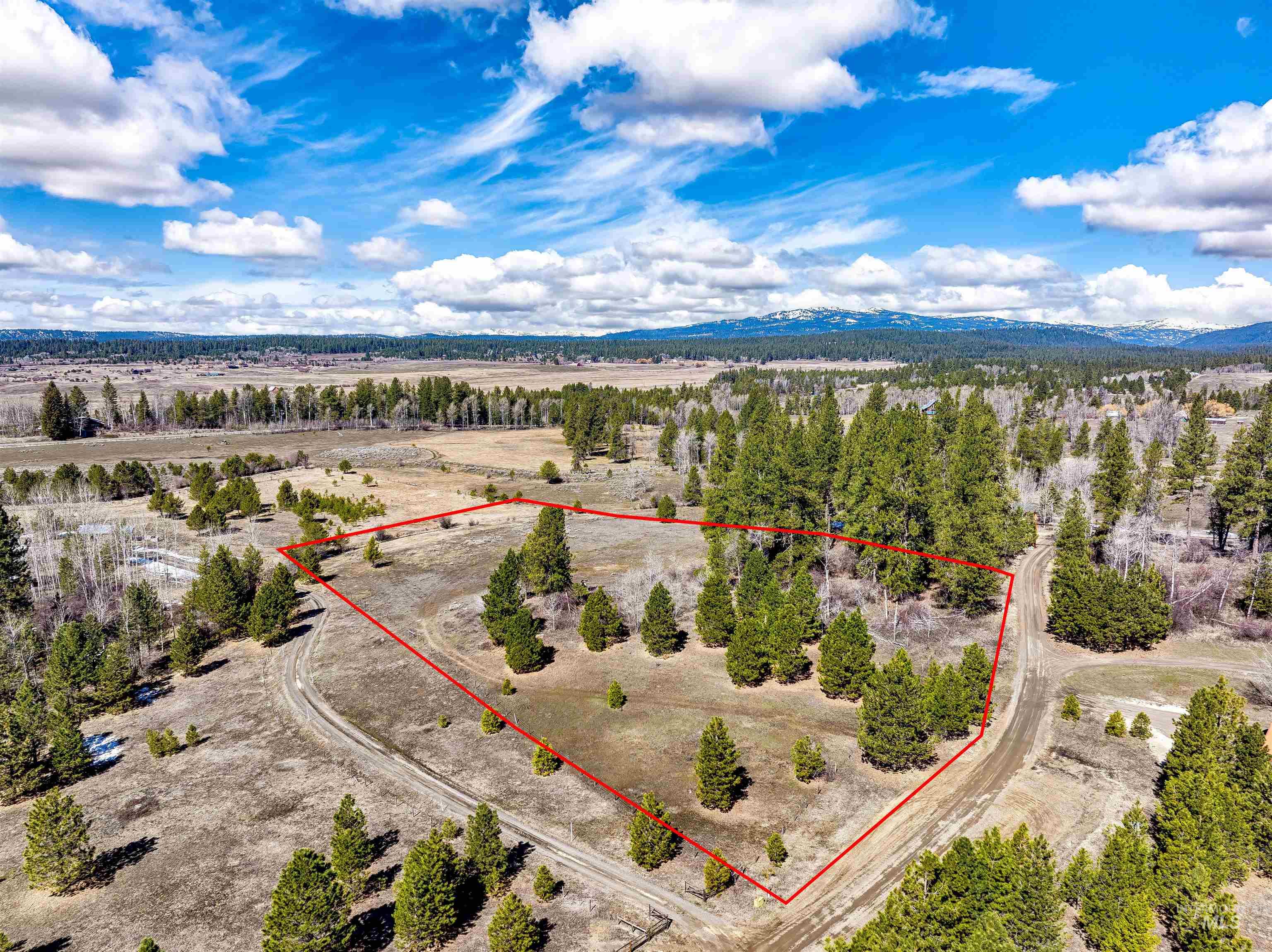 Aerial view of sparsely populated area featuring property parcel outlined and a mountain backdrop