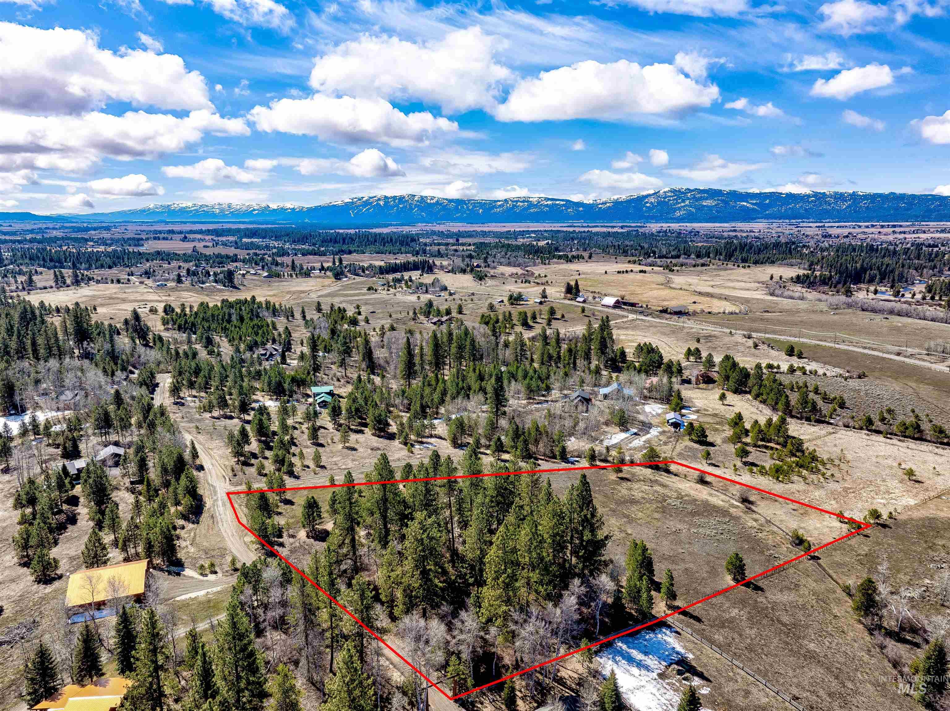 Aerial view of sparsely populated area featuring a mountain backdrop and property parcel outlined