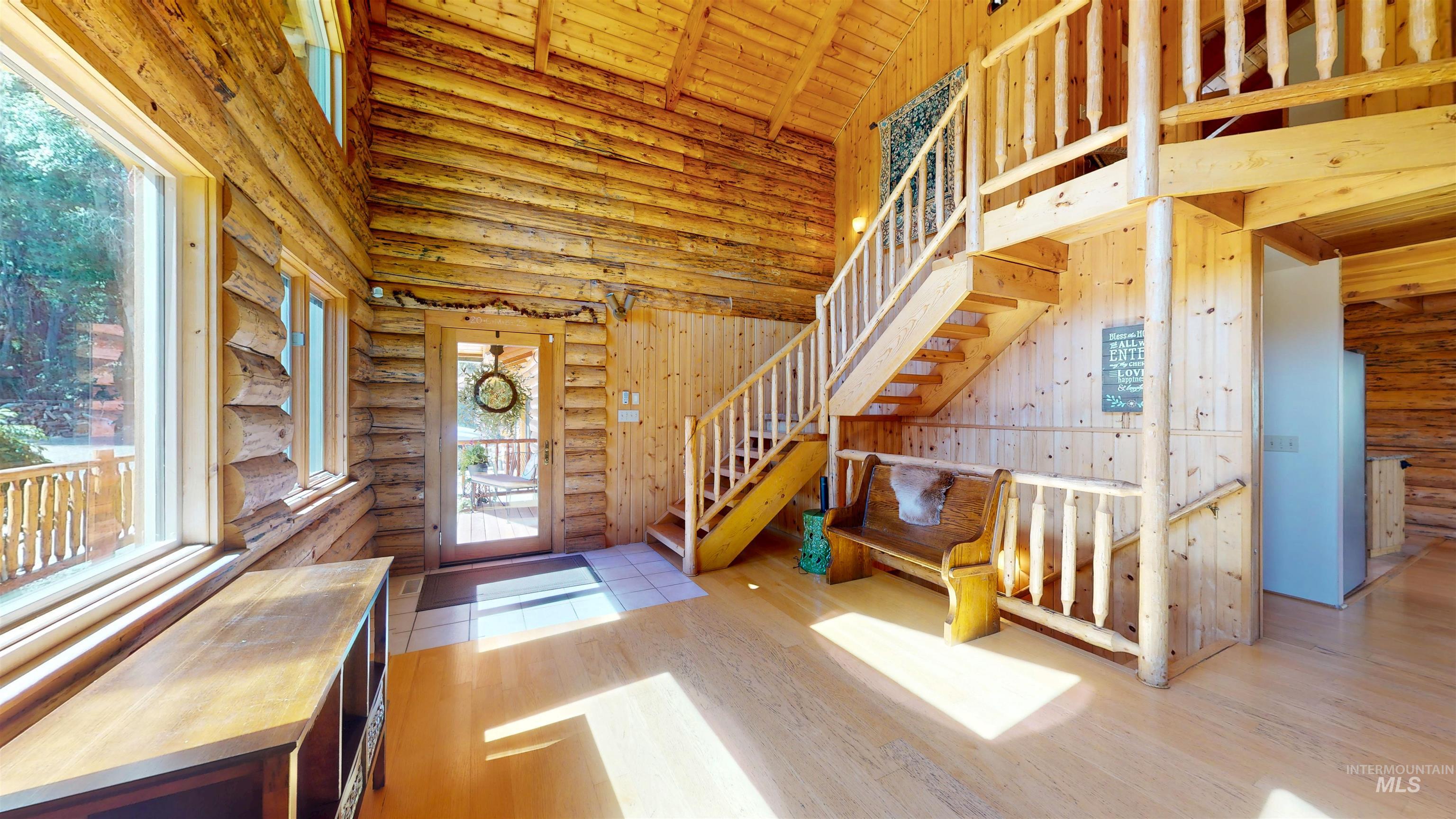 Entrance foyer featuring rustic walls, high vaulted ceiling, stairway, wood finished floors, and wood ceiling
