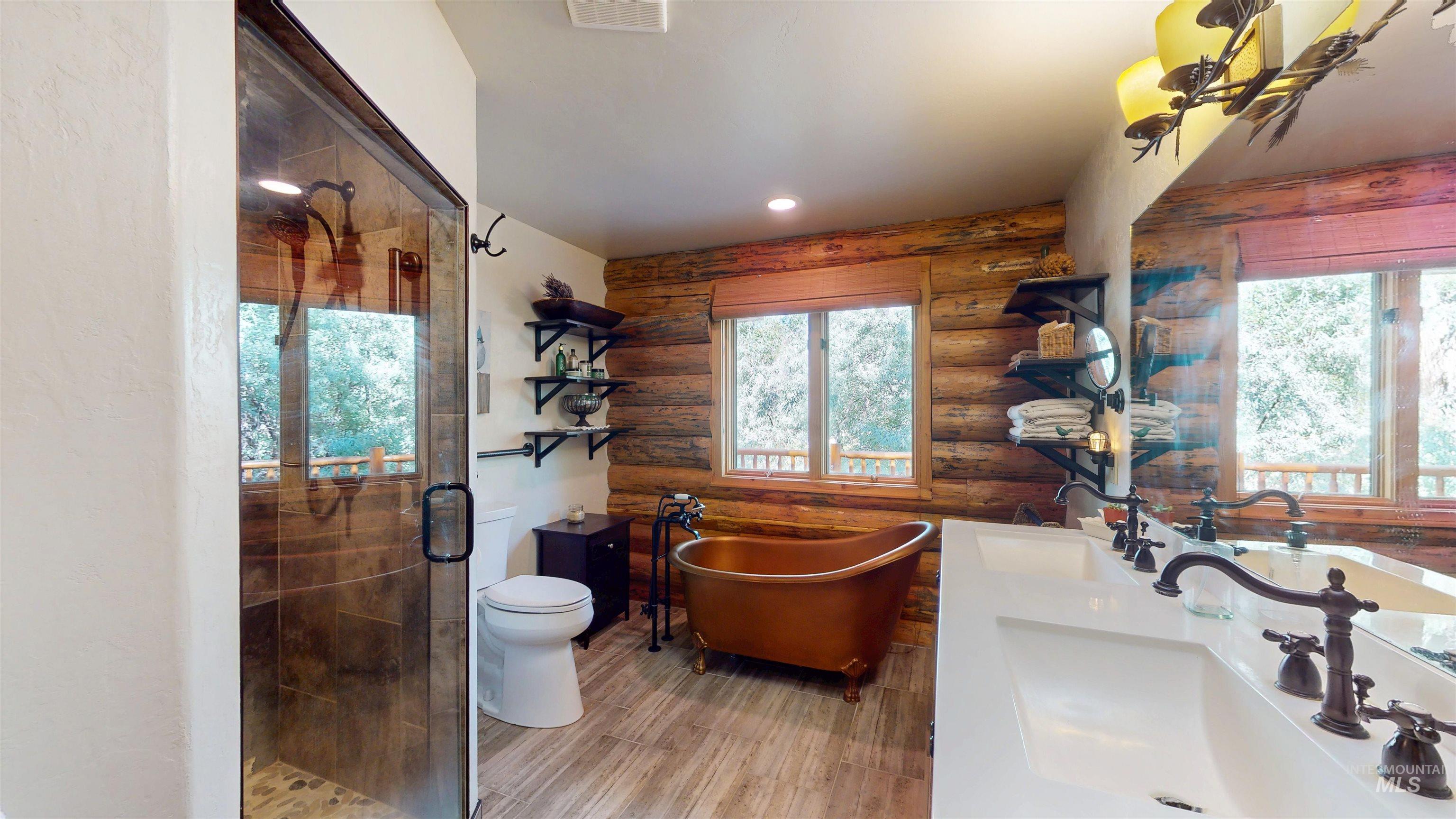 Full bath featuring rustic walls, plenty of natural light, a stall shower, a soaking tub, and double vanity