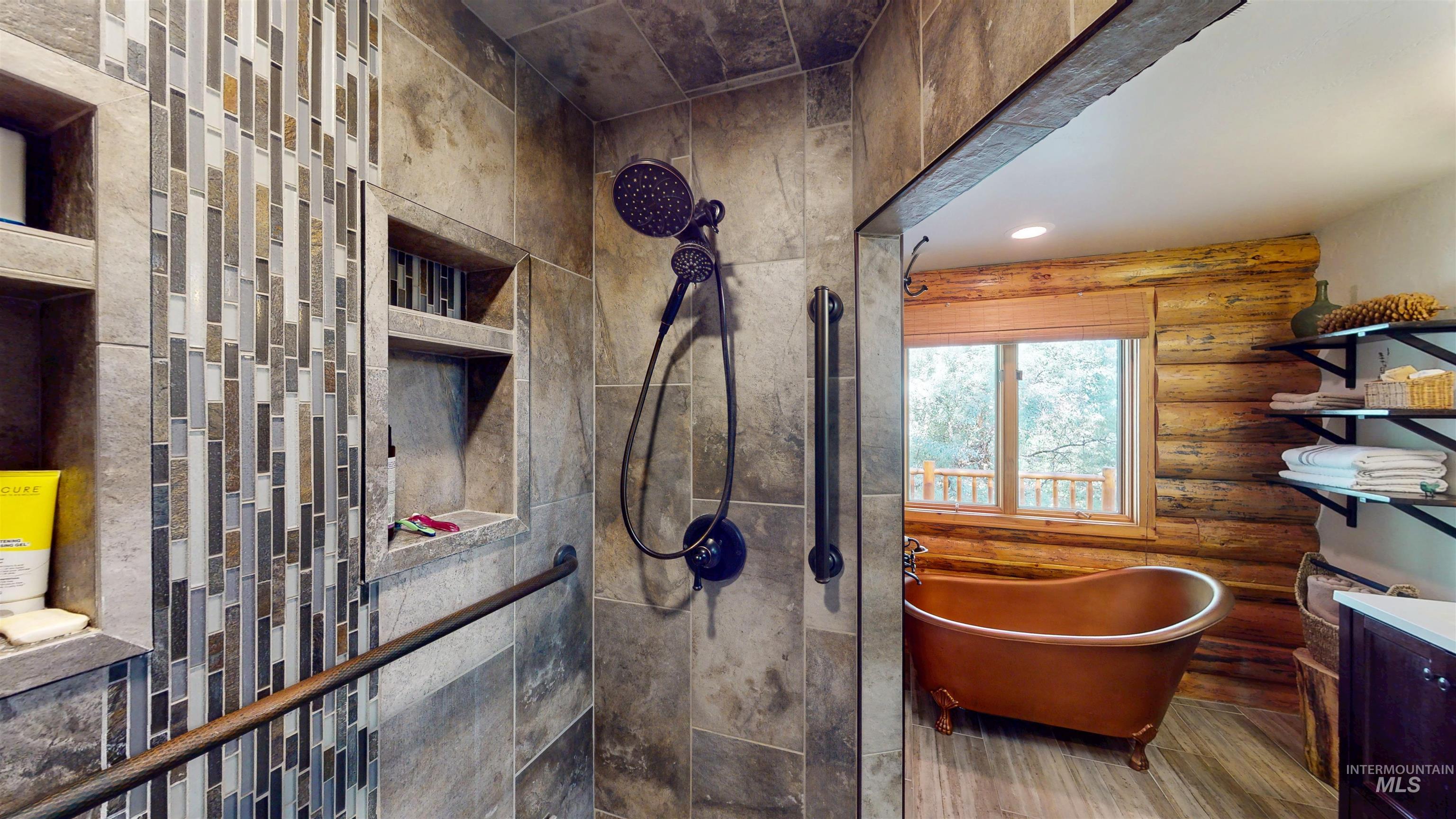 Bathroom with a soaking tub, wood finished floors, log walls, tiled shower, and vanity