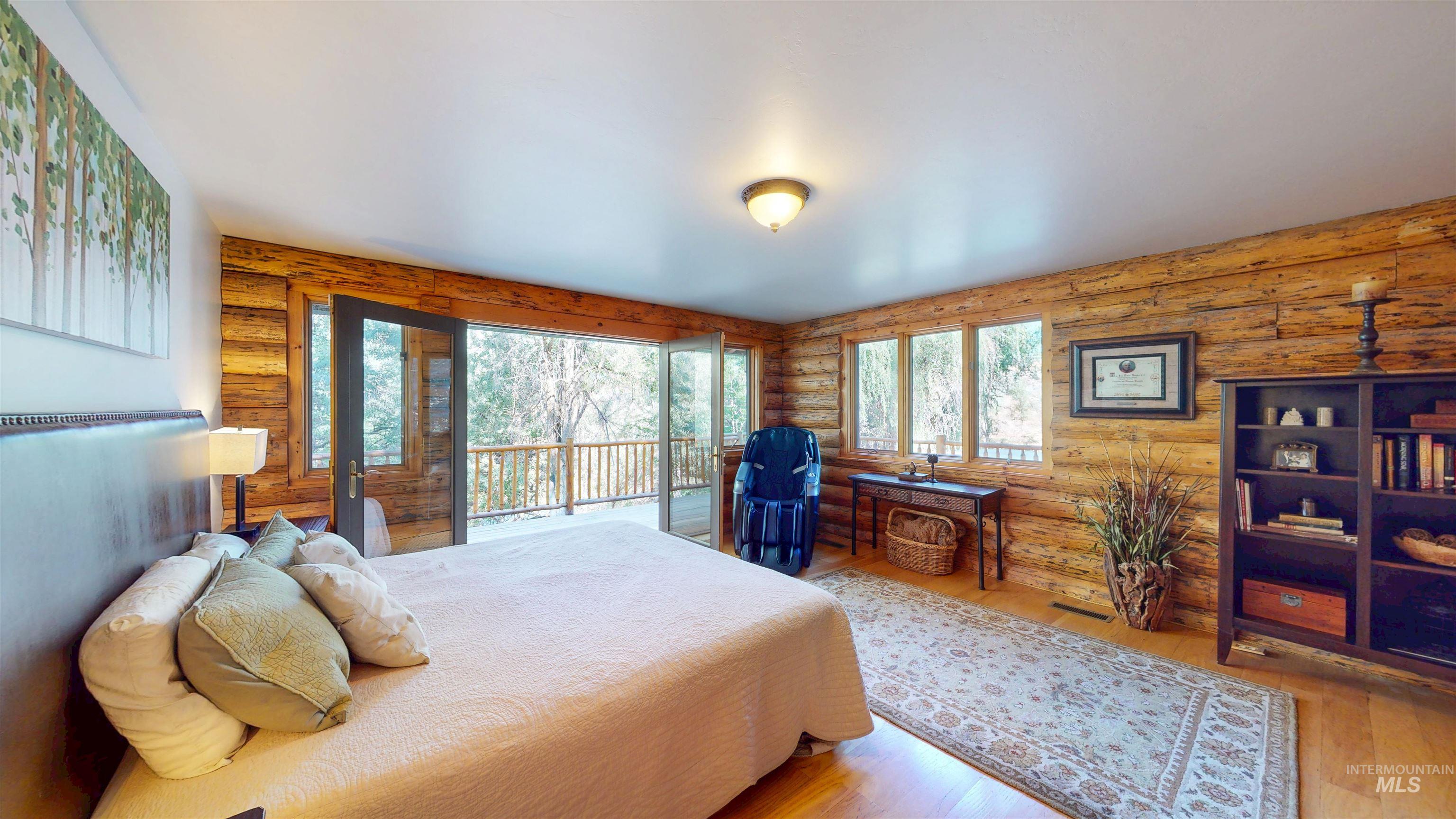 Bedroom with access to outside, rustic walls, and wood finished floors