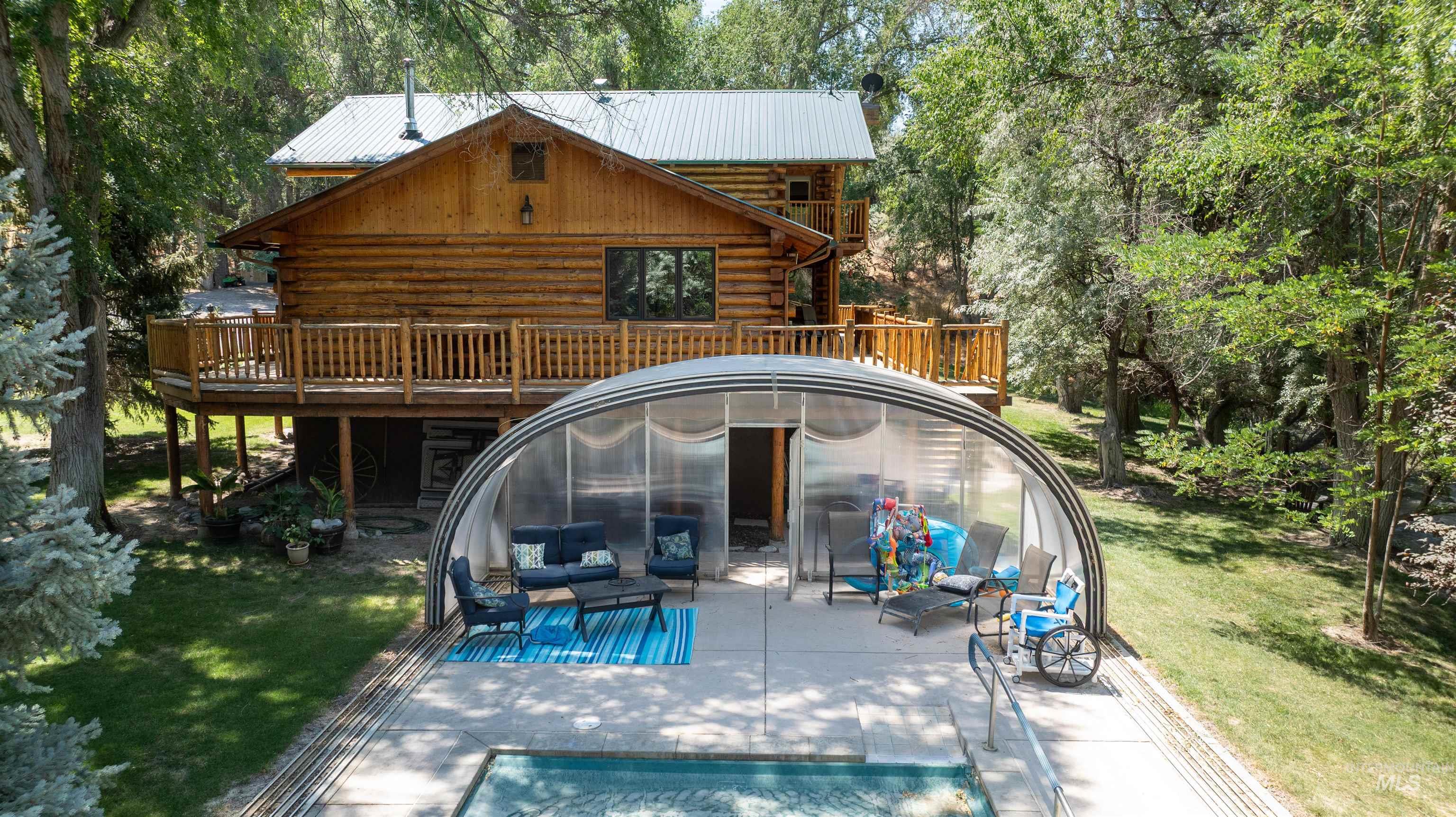 Rear view of house featuring log siding, a yard, a deck, a patio area, and a metal roof