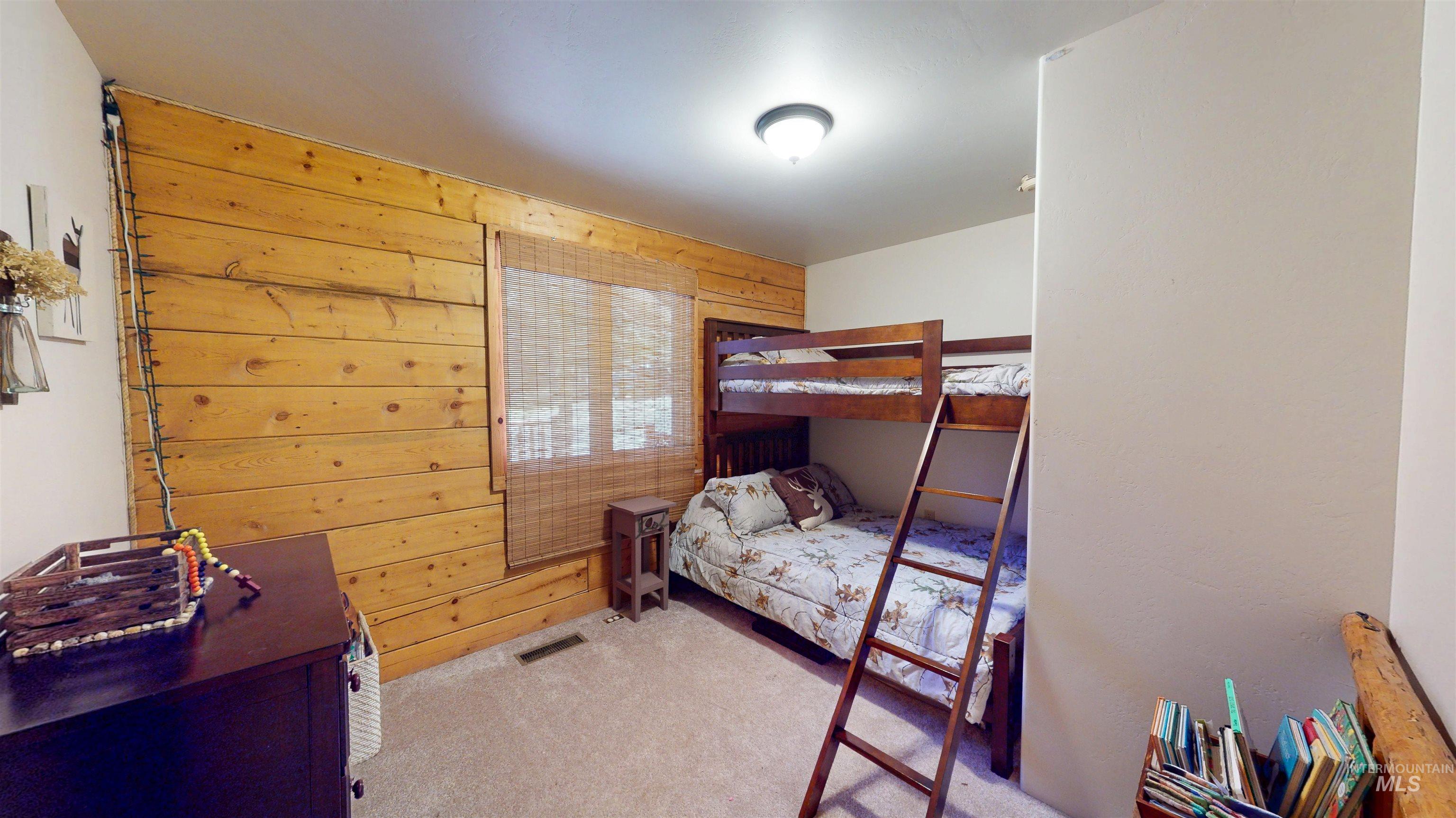 Carpeted bedroom featuring wooden walls