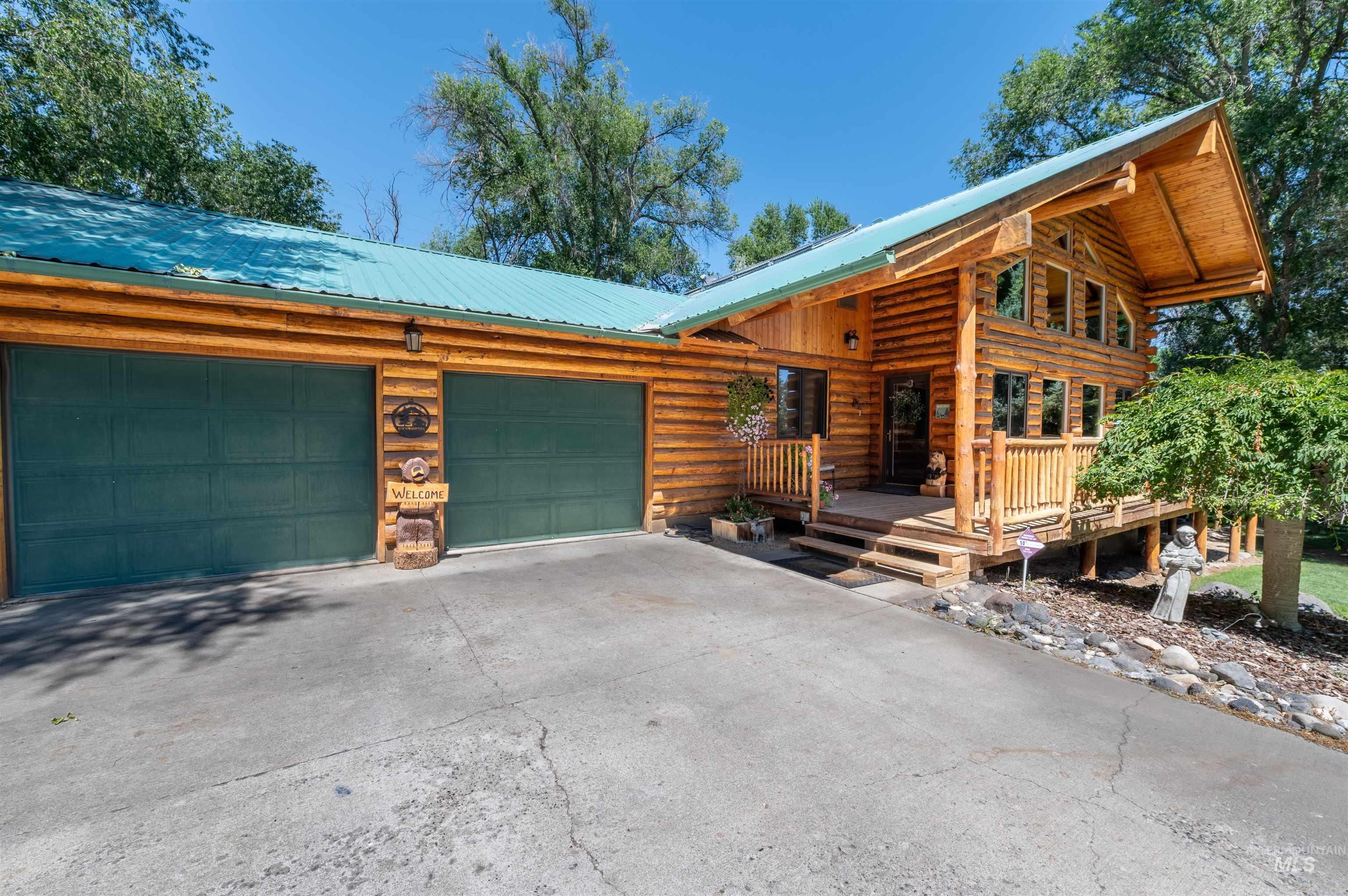 Cabin with an attached garage, concrete driveway, a metal roof, and log siding