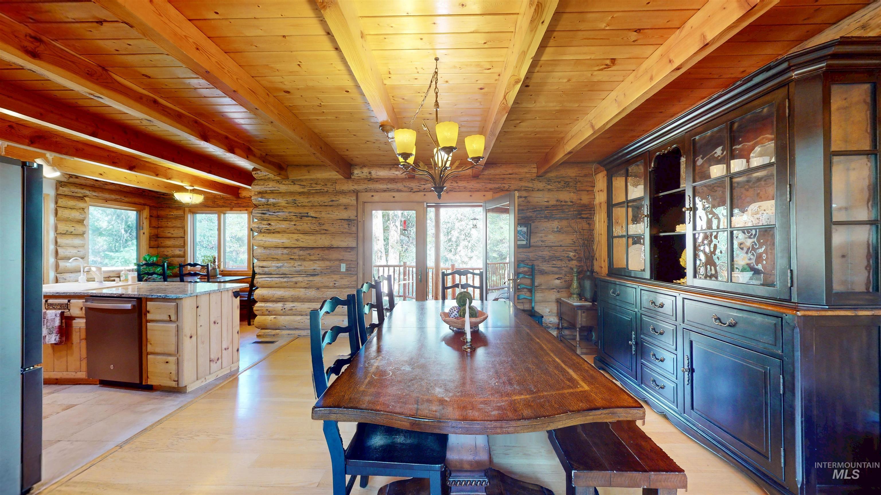 Dining room featuring log walls, a wooden ceiling with exposed beams, a chandelier, and light wood-style flooring