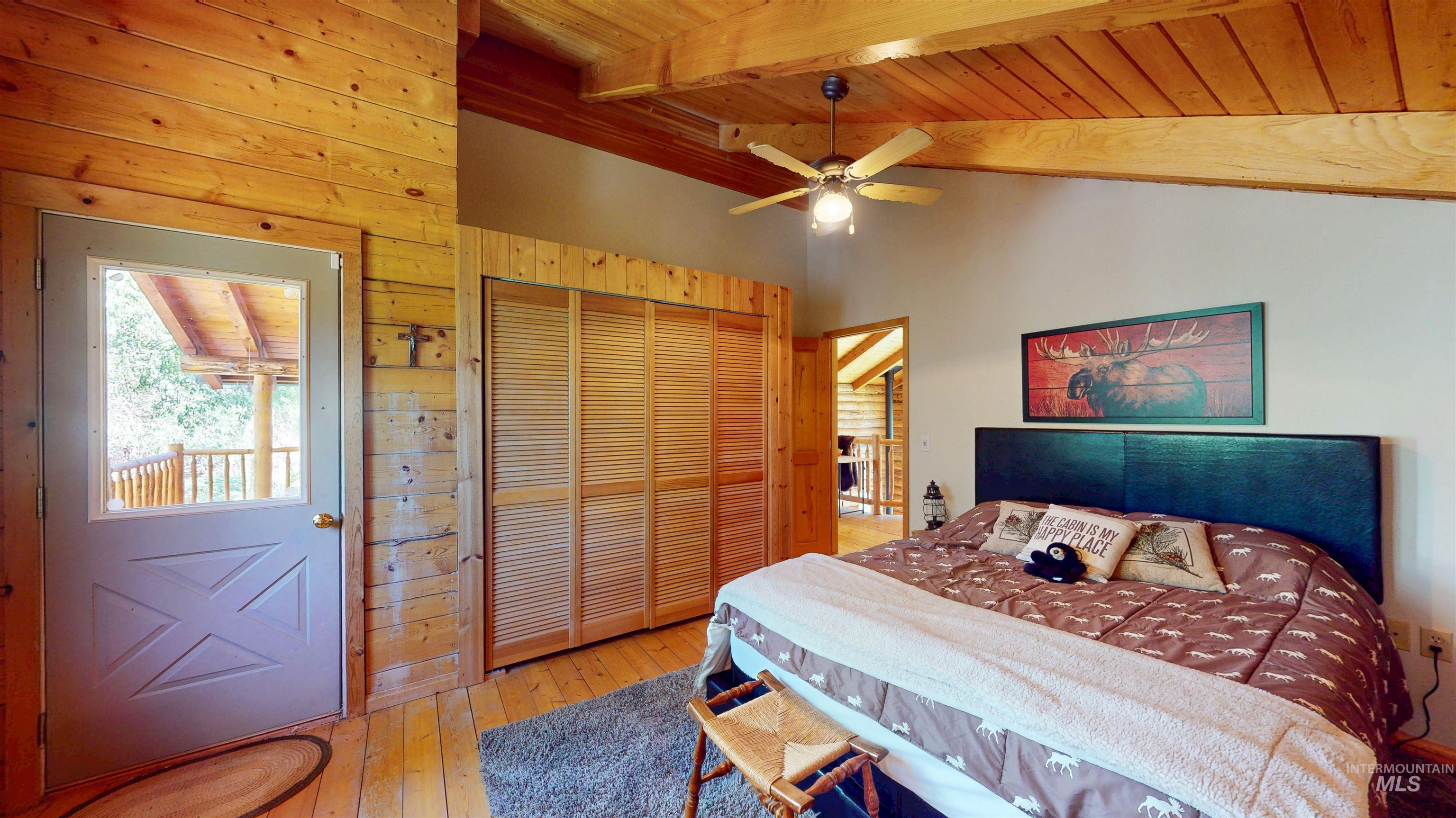 Bedroom with wooden walls, wooden ceiling, hardwood / wood-style flooring, a closet, and ceiling fan