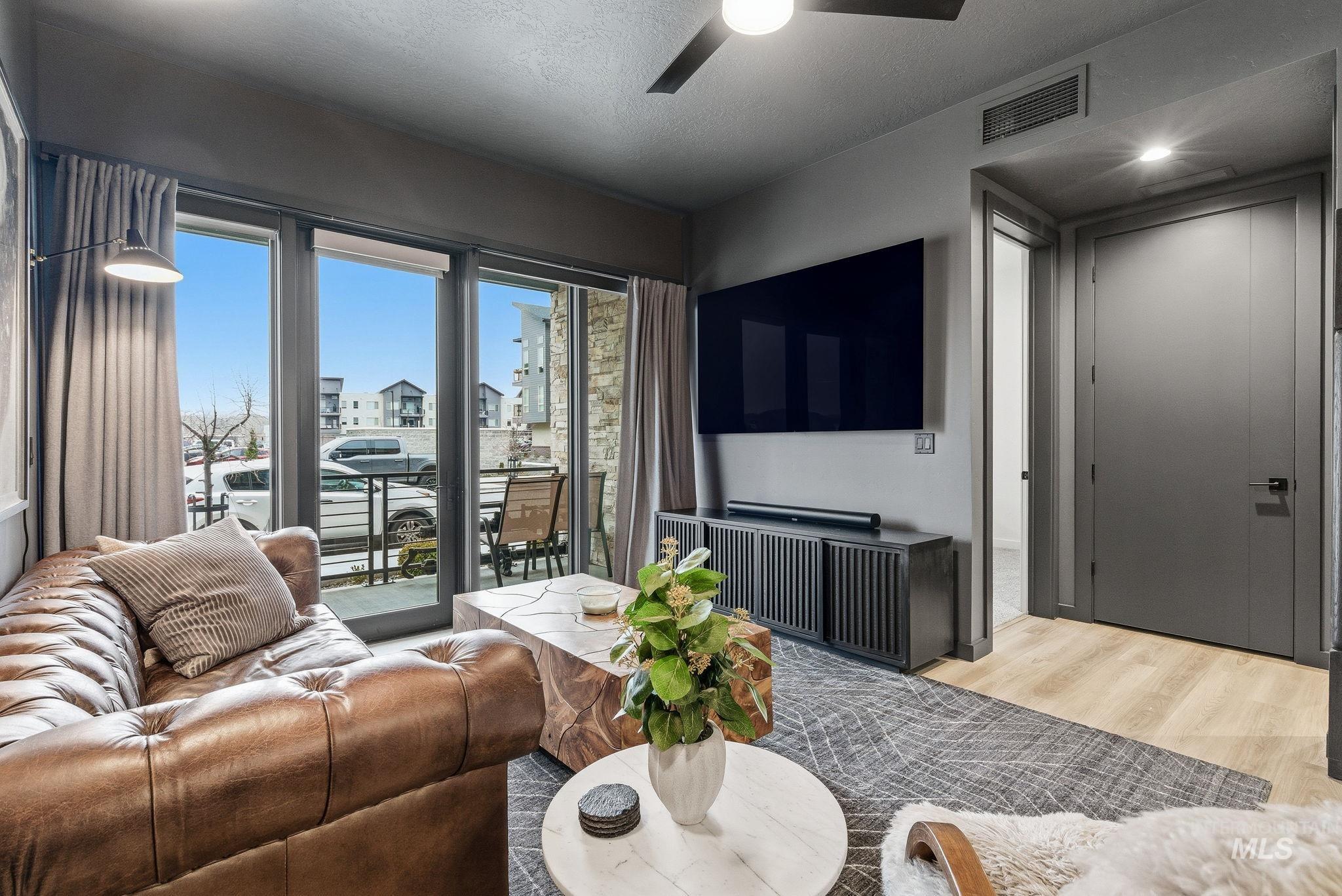 Living area featuring a ceiling fan, wood finished floors, and a textured ceiling