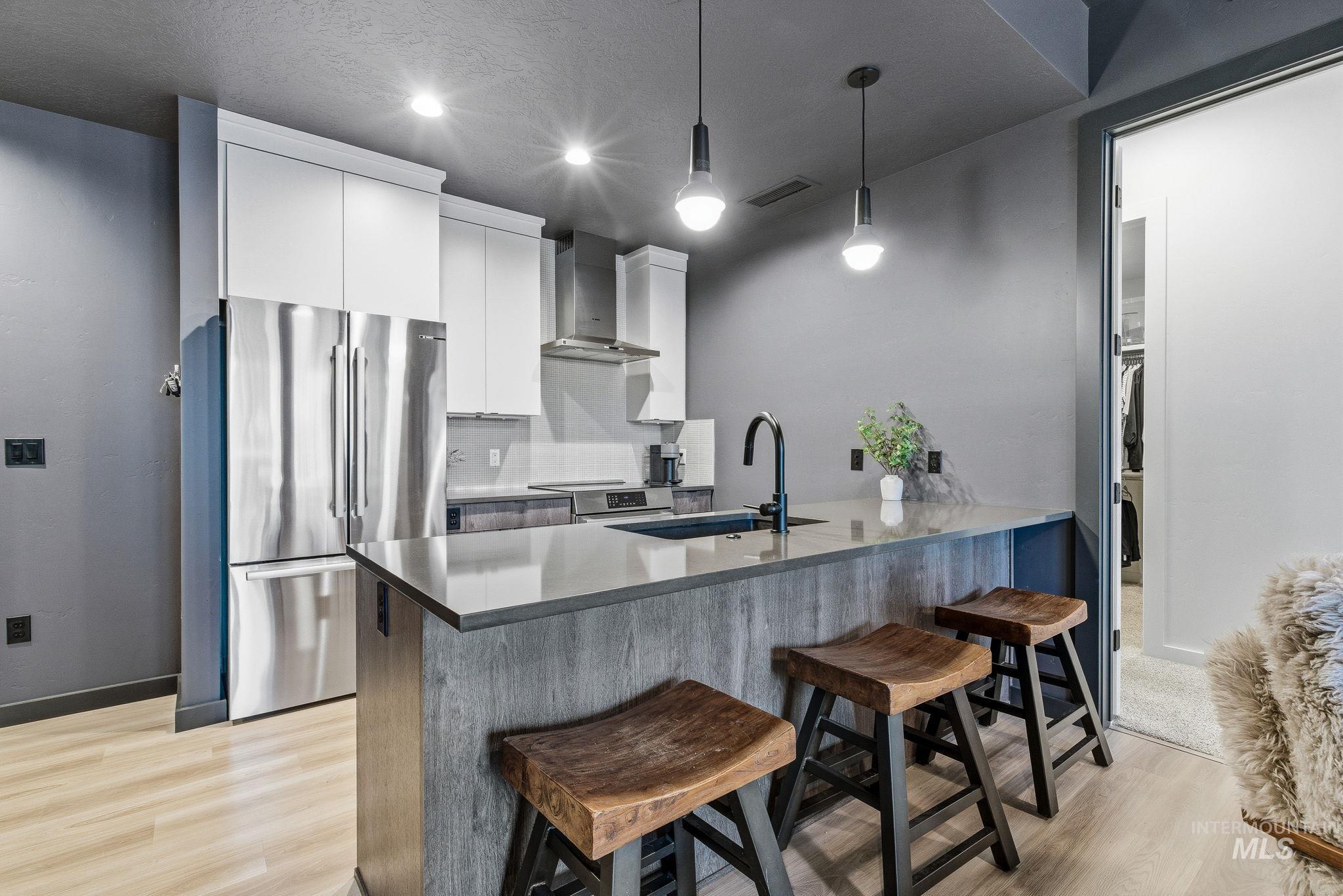 Kitchen featuring stainless steel appliances, a breakfast bar area, modern cabinets, white cabinetry, and light wood-style floors