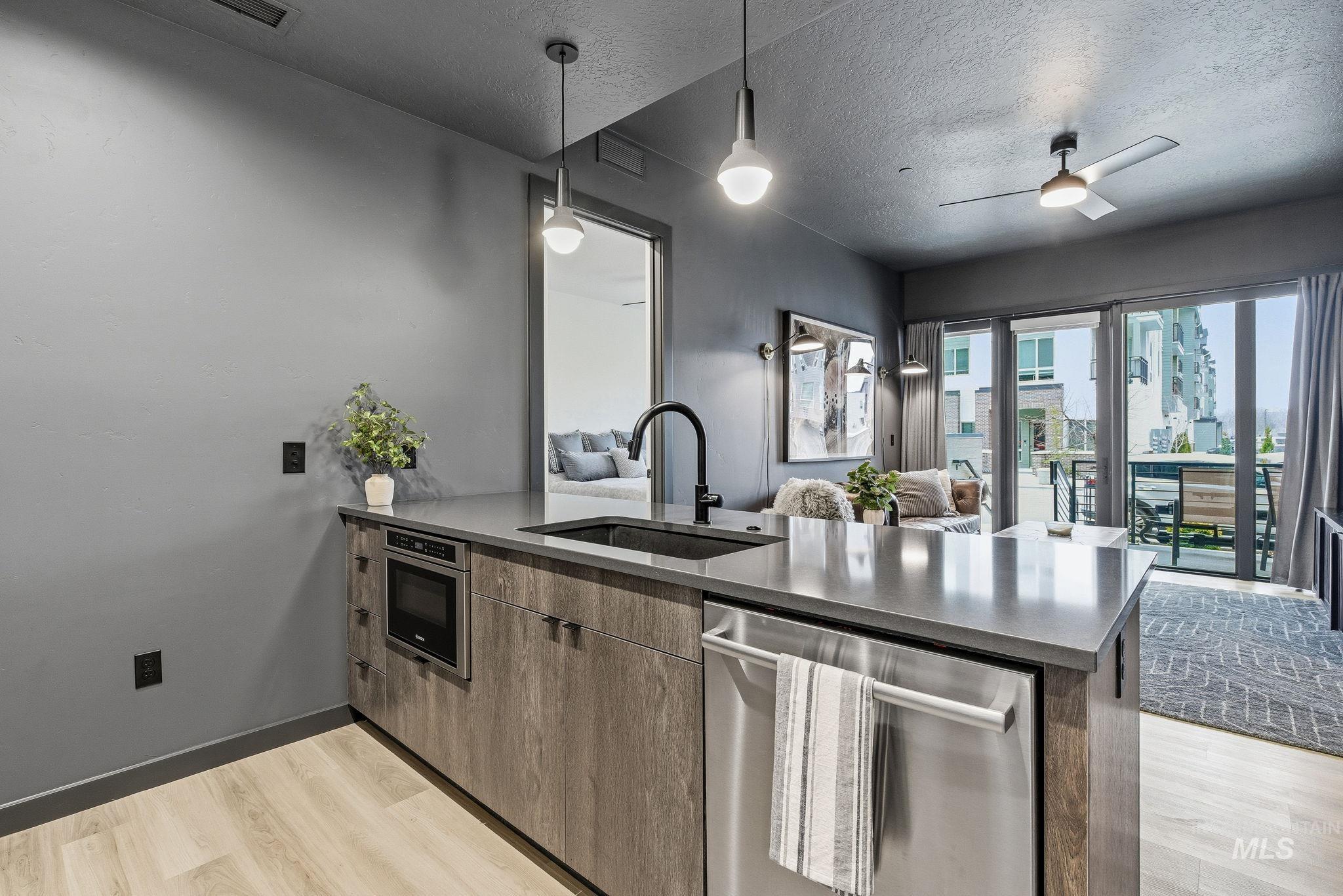 Kitchen featuring stainless steel appliances, a peninsula, open floor plan, decorative light fixtures, and a textured ceiling