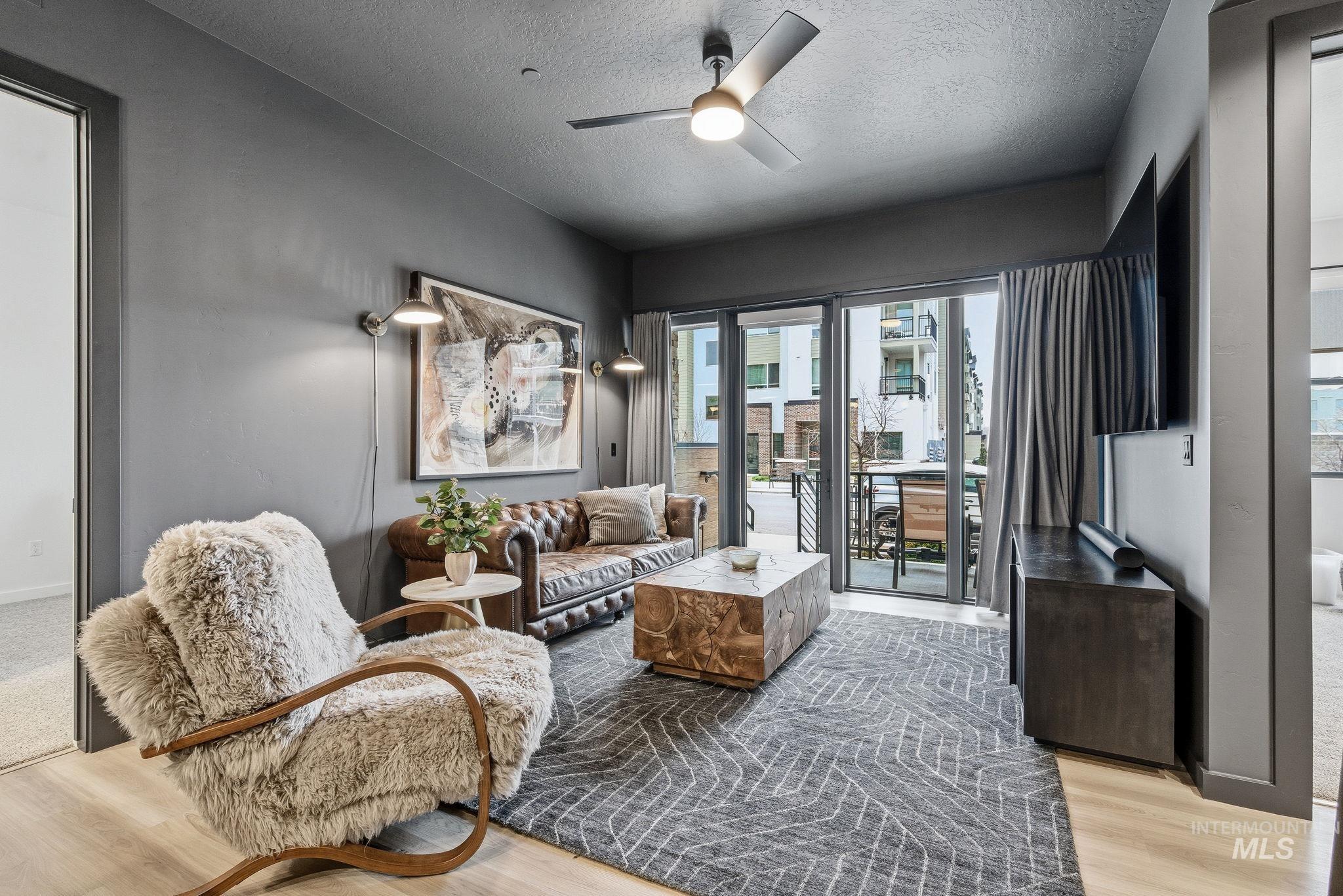 Living room featuring a ceiling fan, light wood-type flooring, and a textured ceiling