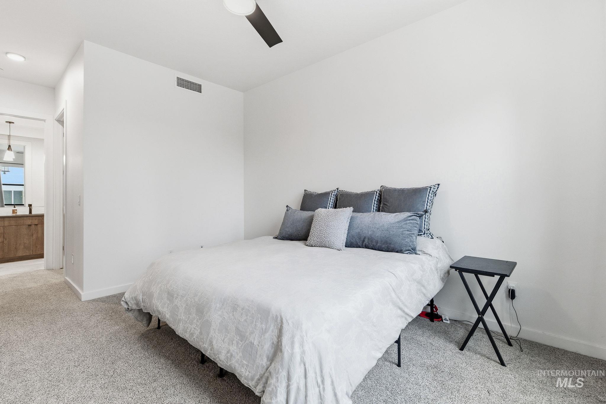 Bedroom featuring carpet floors, a ceiling fan, and connected bathroom