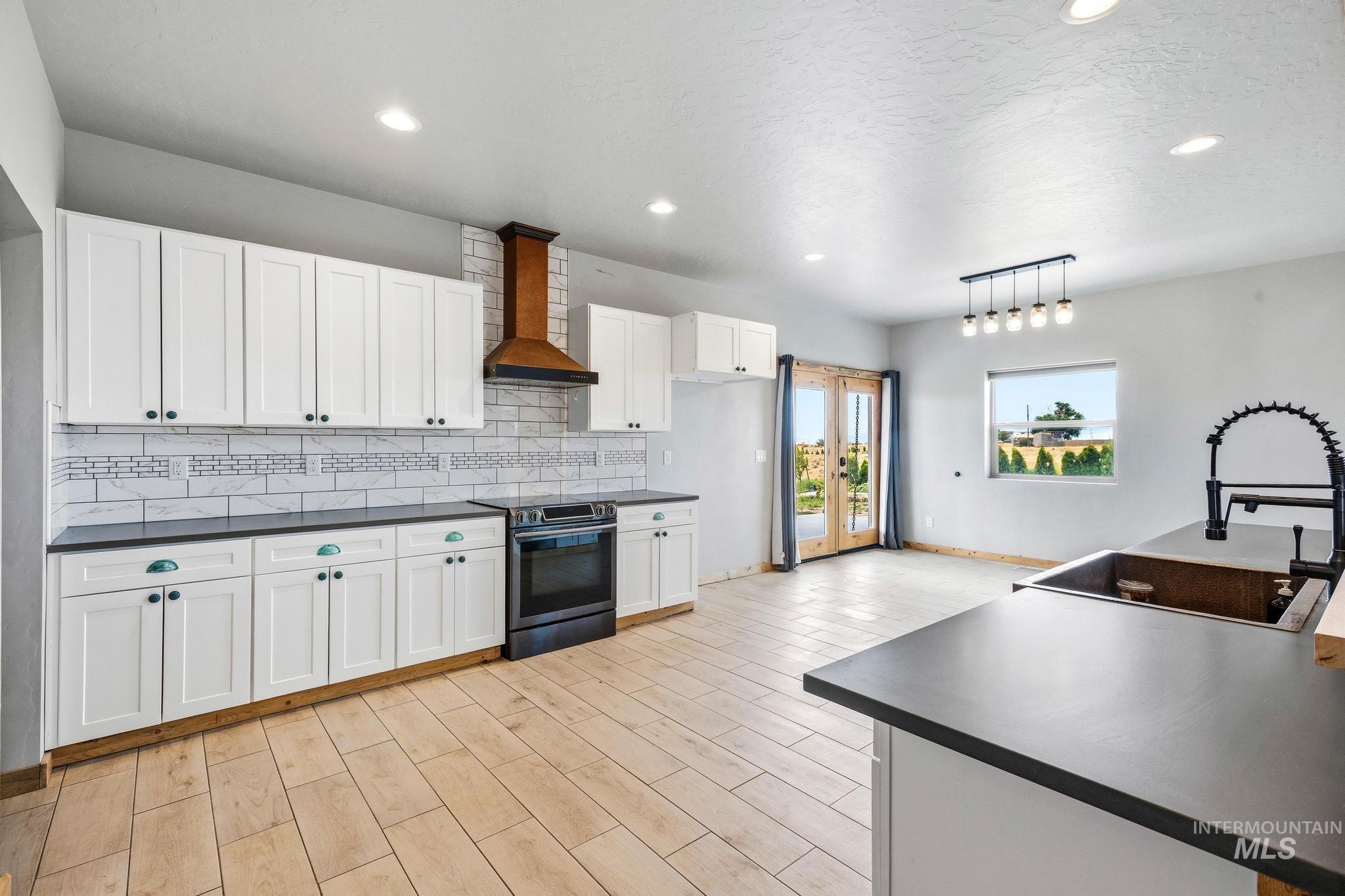 Kitchen featuring white cabinetry with dark hardware, dark countertops, and a subway tile backsplash