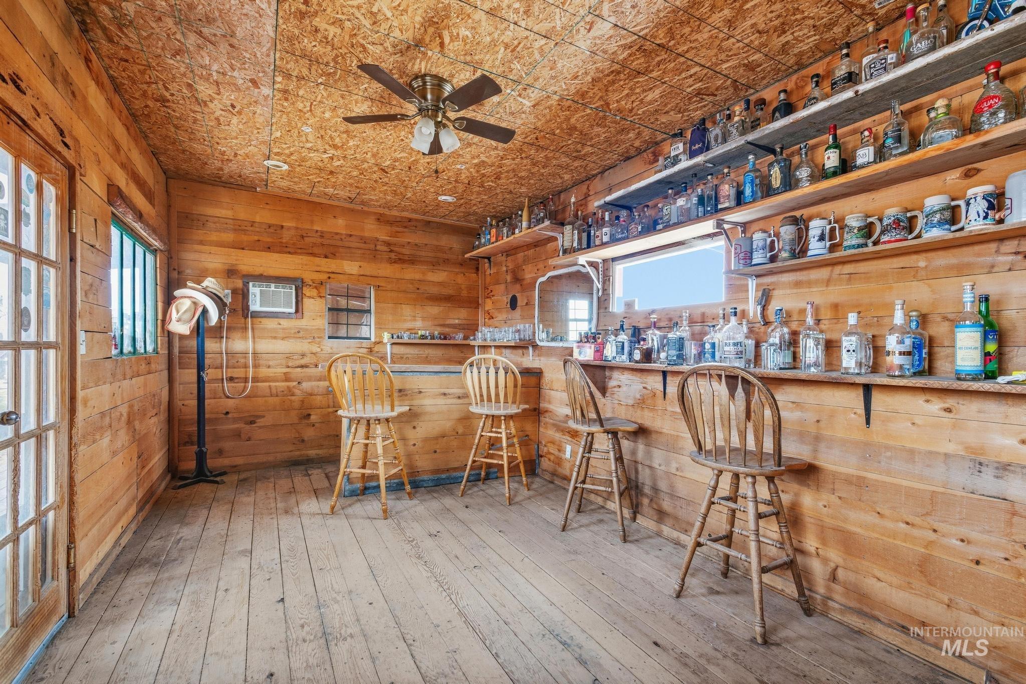 Wood-paneled interior featuring a built-in bar, wood-finish flooring, and a ceiling fan