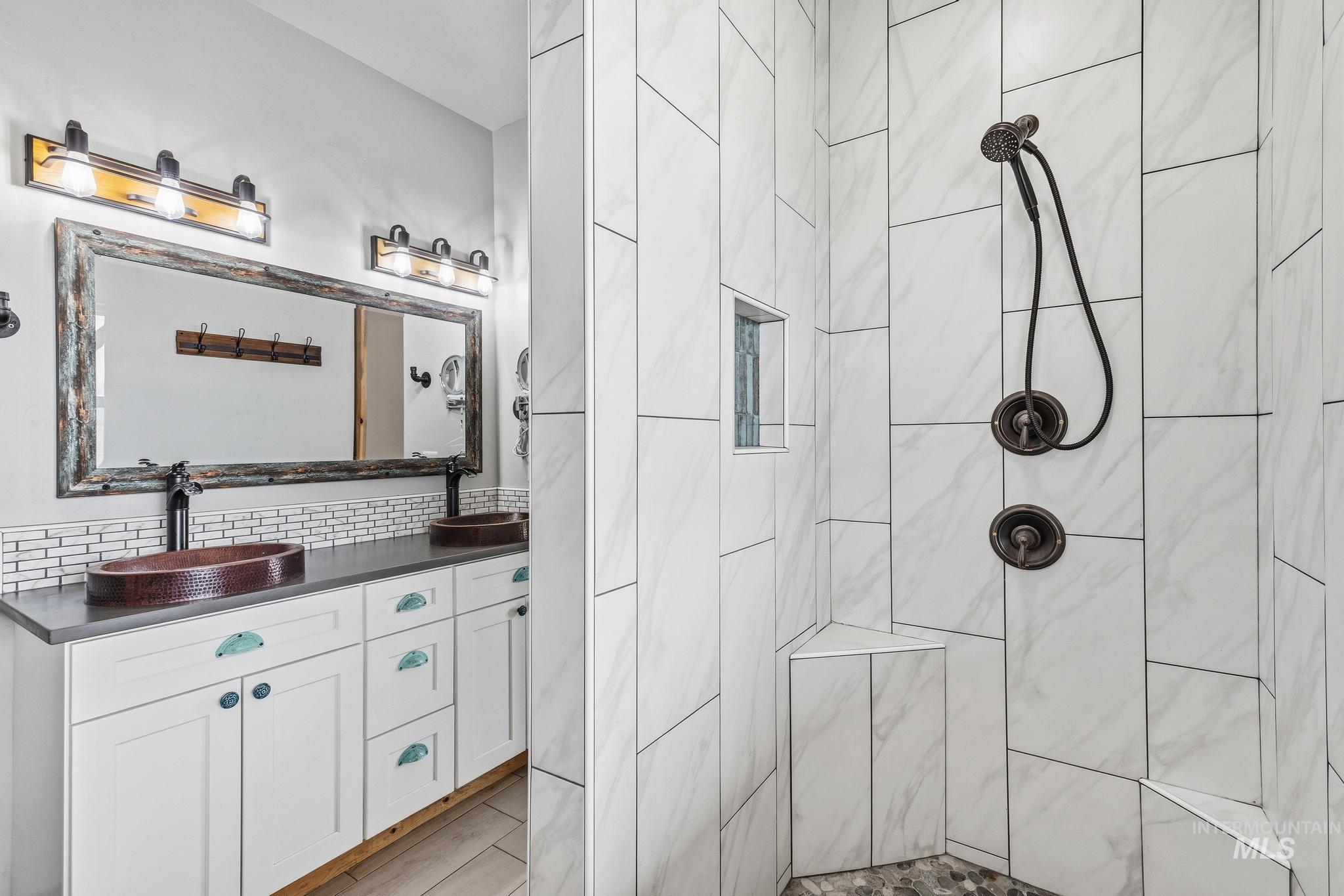 Dual vanity with copper vessel sinks, a distressed wood-frame mirror, and a tile backsplash