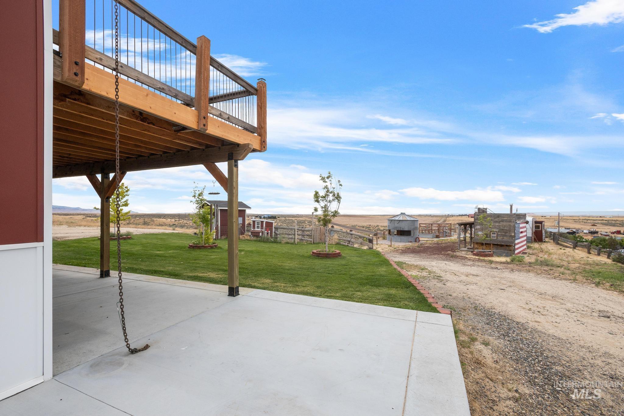 Expansive concrete patio with an overhead wooden deck featuring black metal railing