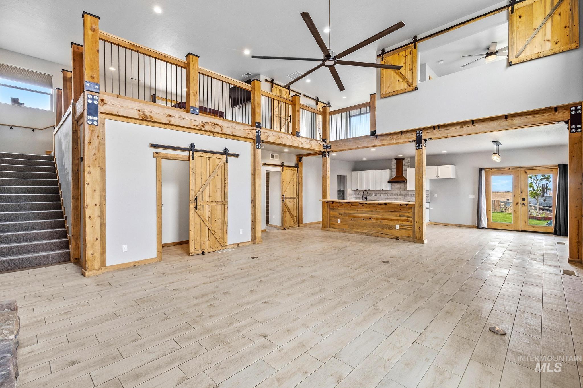 Open-concept interior featuring wood-finish flooring, exposed wood beams, and a vaulted ceiling