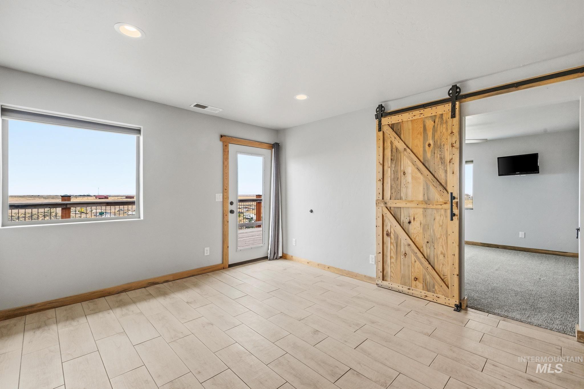 Spacious interior featuring wood-finish tile flooring, recessed lighting, and a prominent barn door