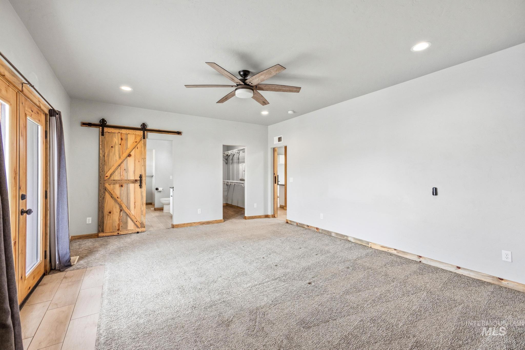 Spacious interior featuring a wood-finish ceiling fan, recessed lighting, and a prominent wood barn door