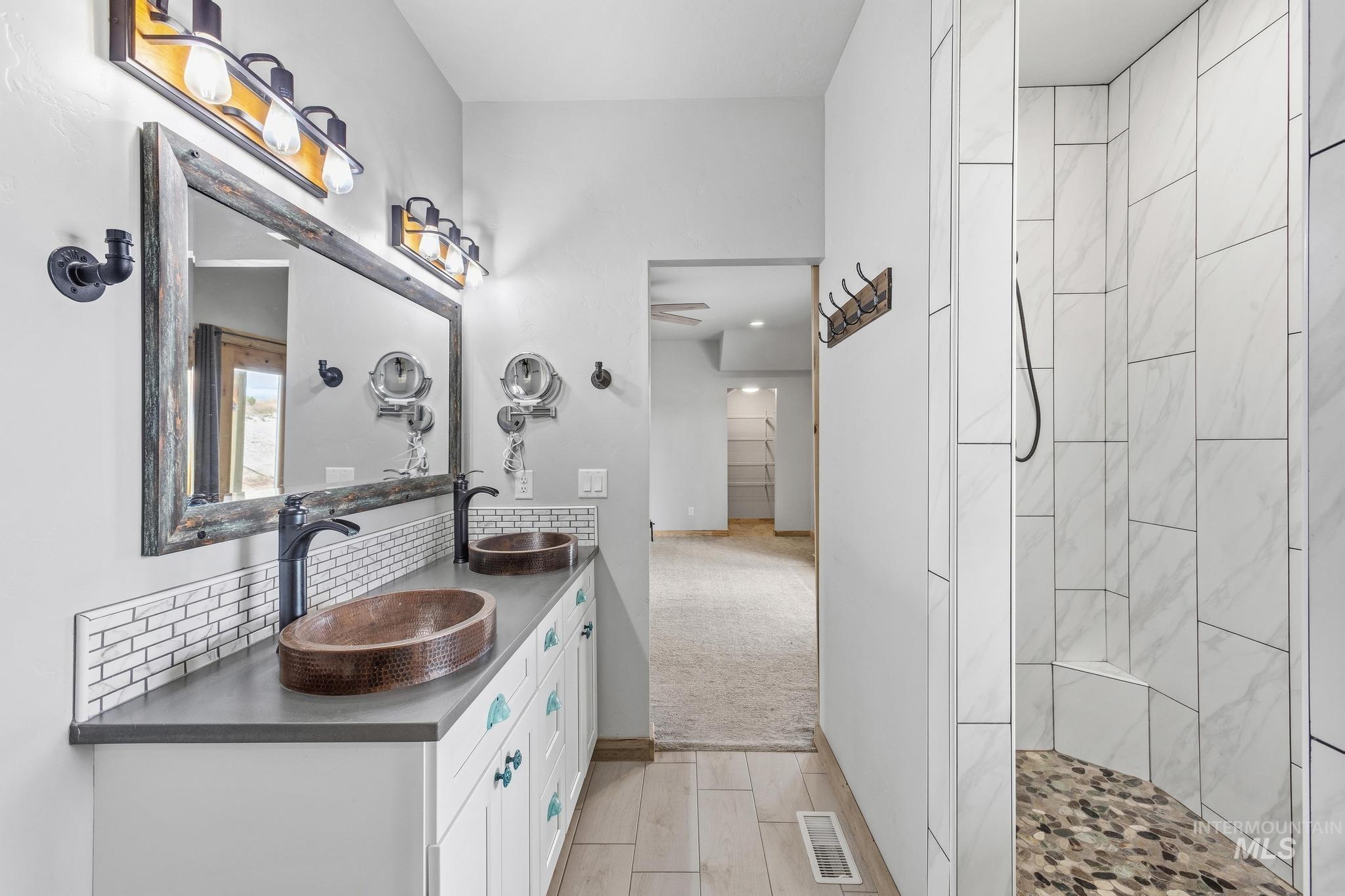 Dual vanity featuring copper vessel sinks, matte black fixtures, and a large framed mirror