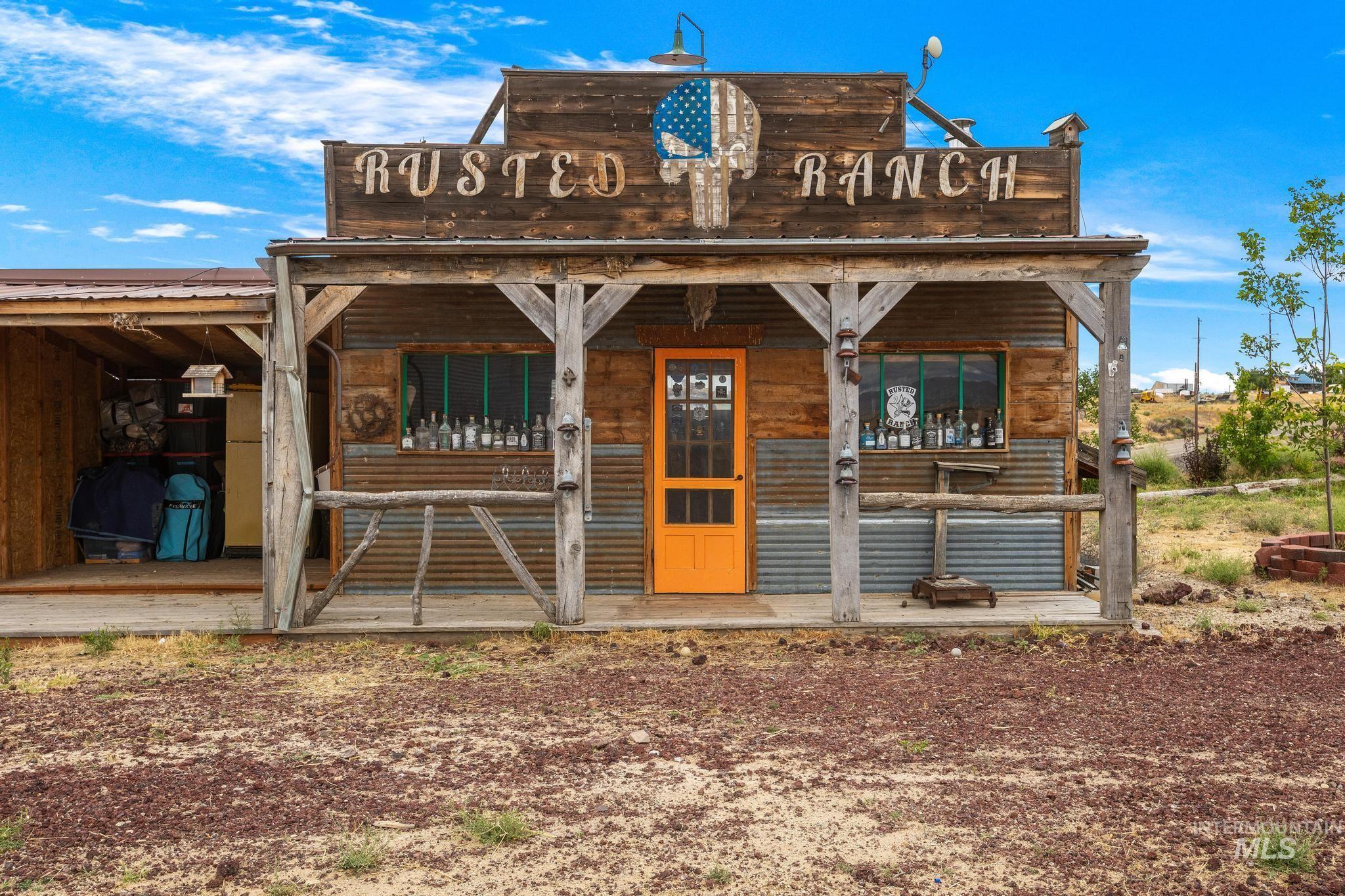 Wood-paneled storefront featuring an orange entry door, corrugated metal accents, and a covered porch with rustic wood posts
