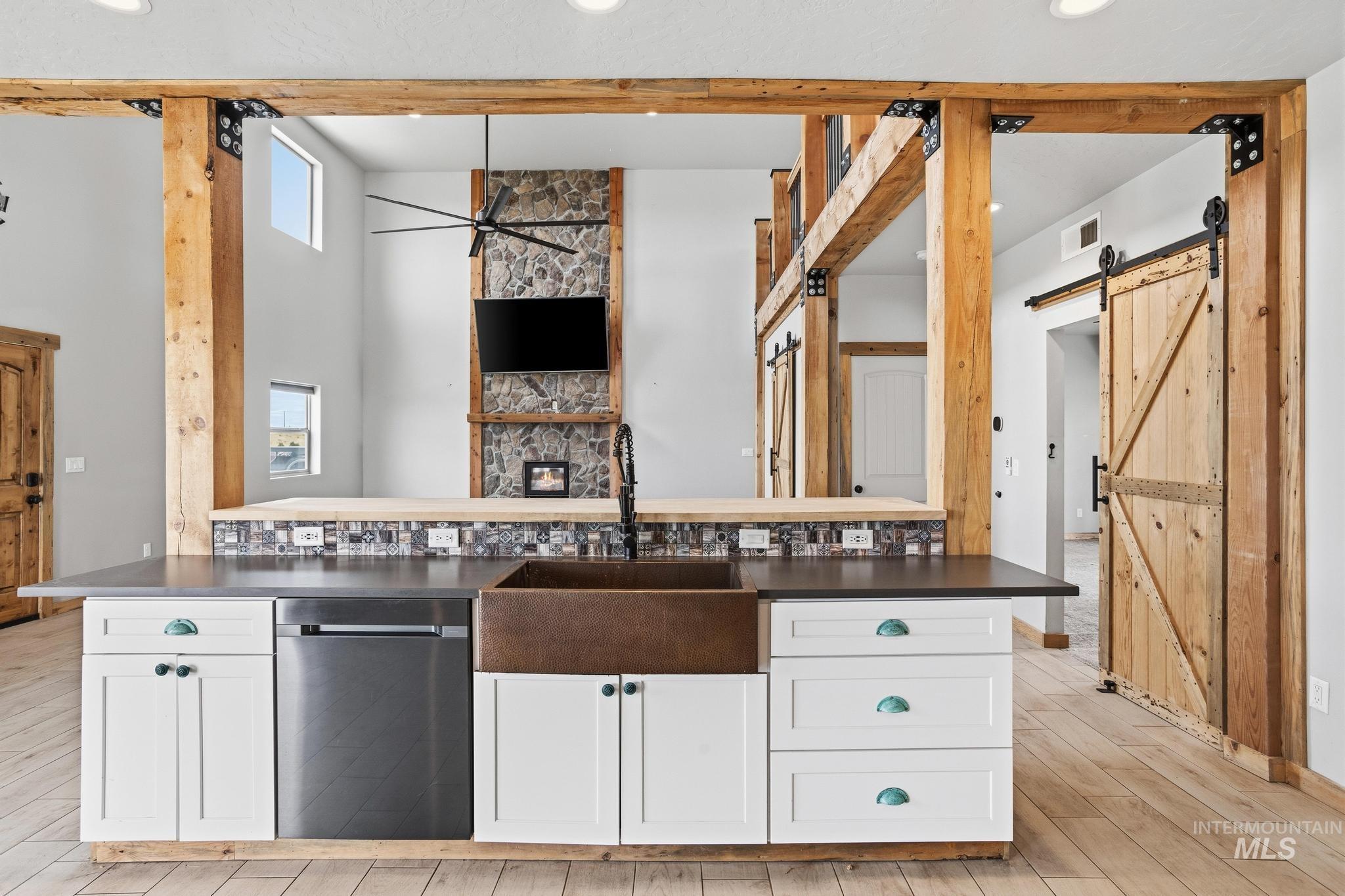 Kitchen island featuring a copper farmhouse sink, dark countertop, and white cabinetry with accent hardware