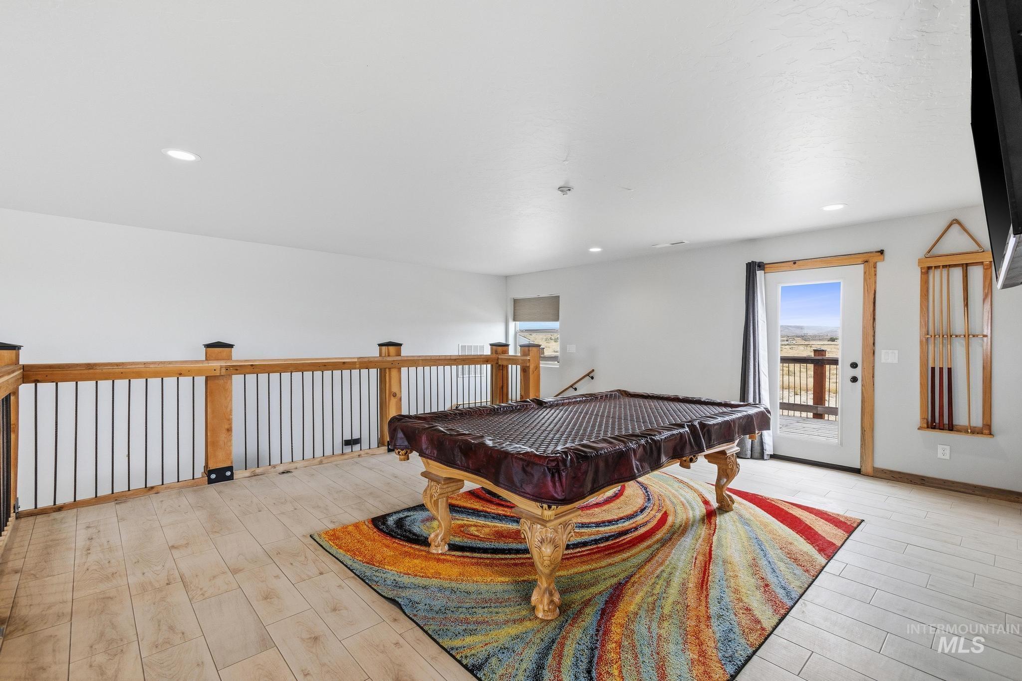 Loft area with light wood-finish flooring and a wood railing featuring black metal spindles