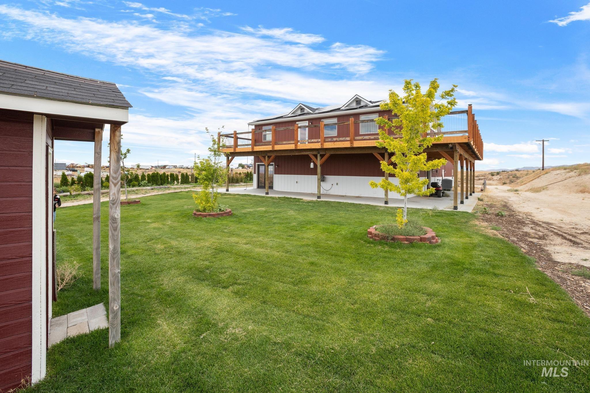 Expansive green lawn with mature trees and a detached red storage shed