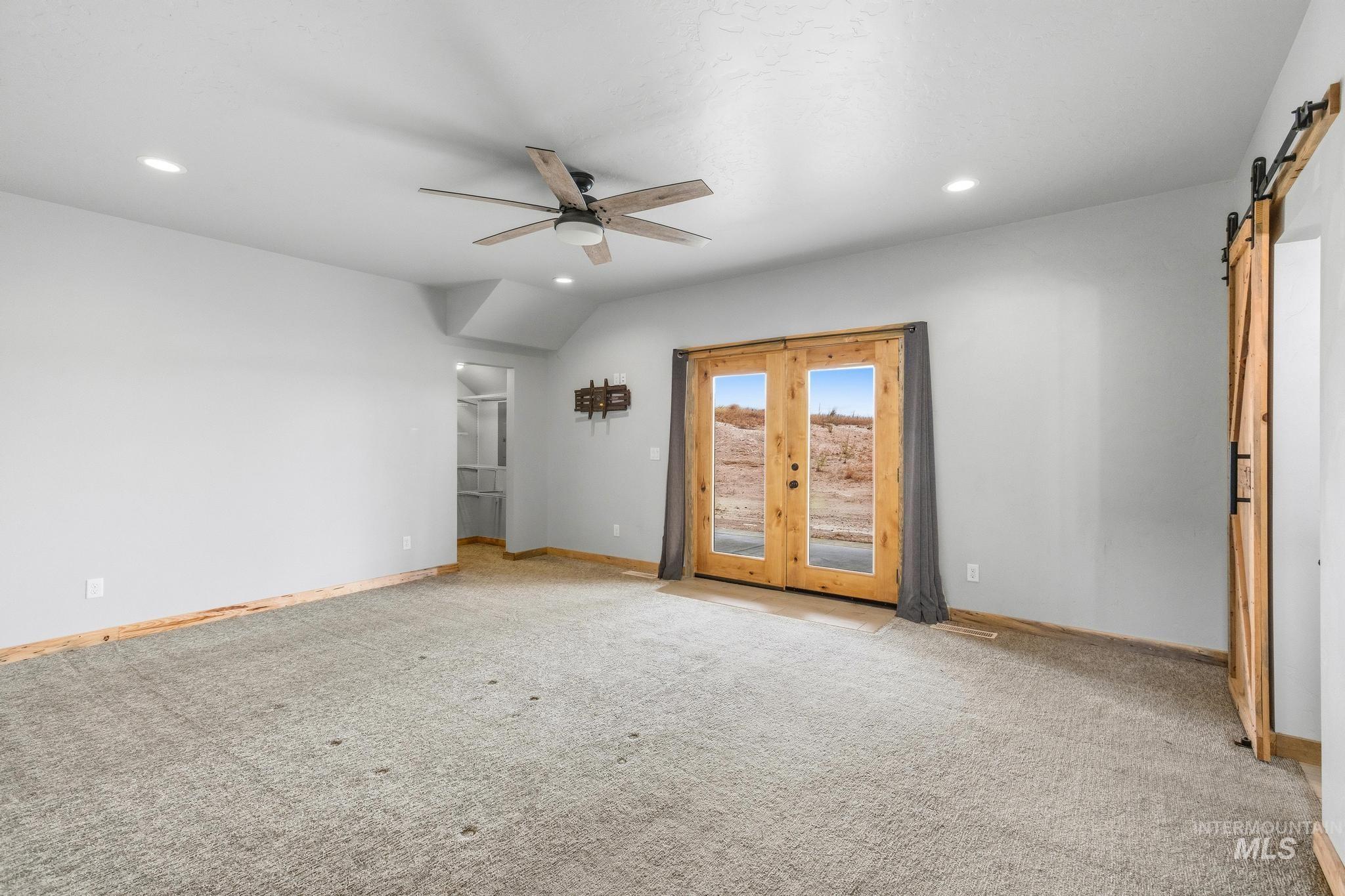 Spacious interior room featuring light gray carpeting and light wood trim