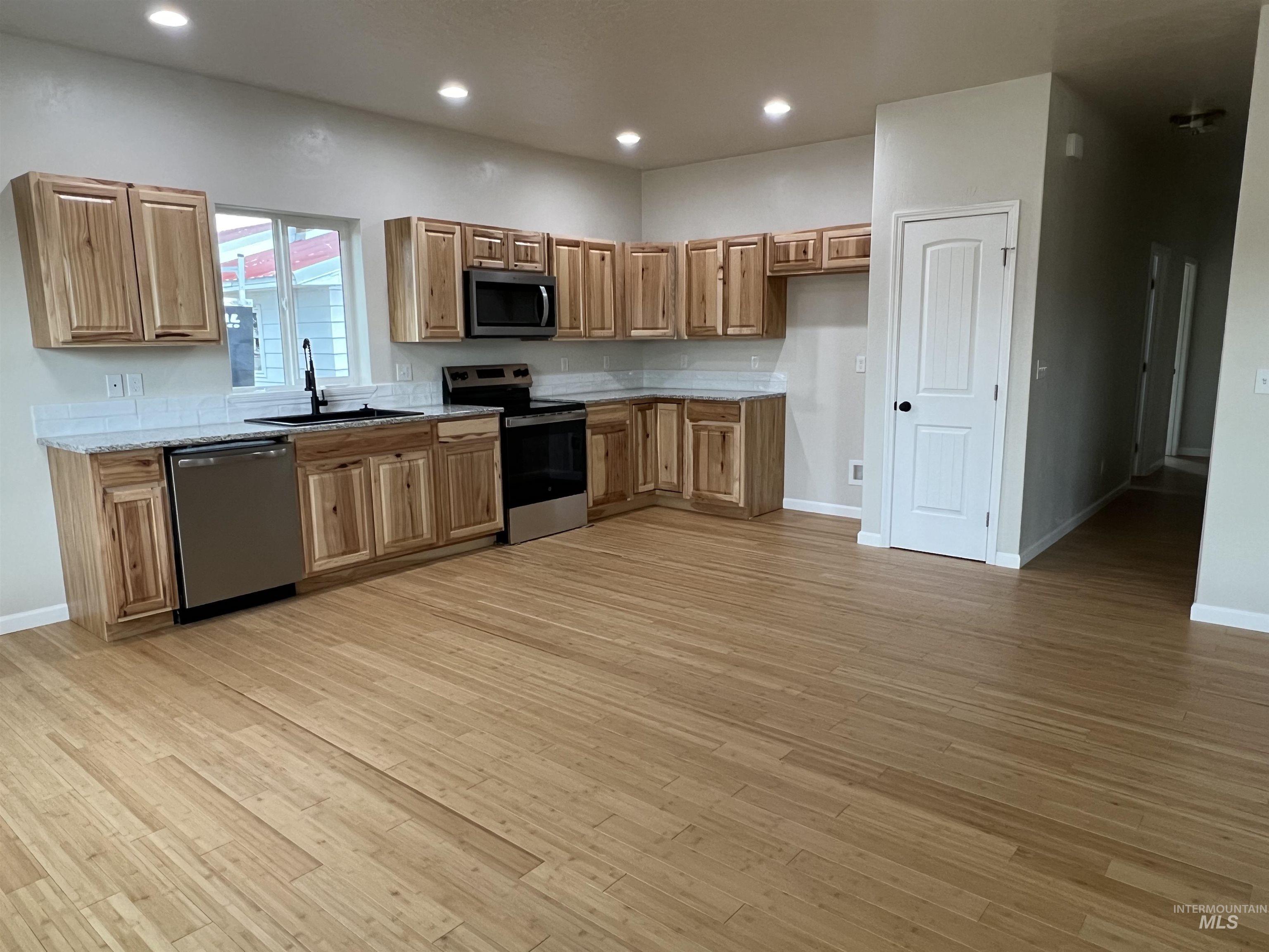 Kitchen featuring stainless steel appliances, recessed lighting, light wood-type flooring, and brown cabinets