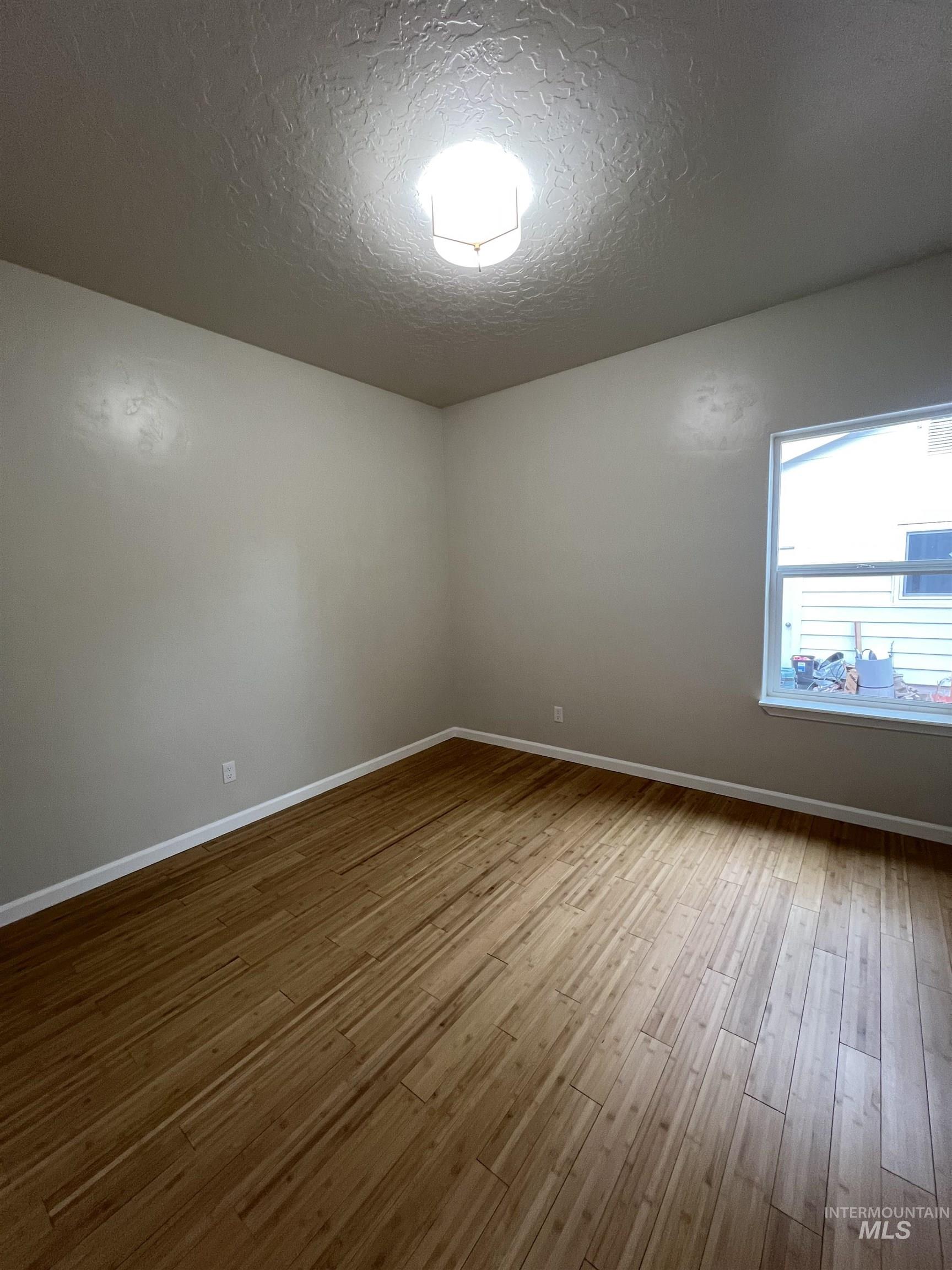 Spare room with a textured ceiling and light wood-style flooring