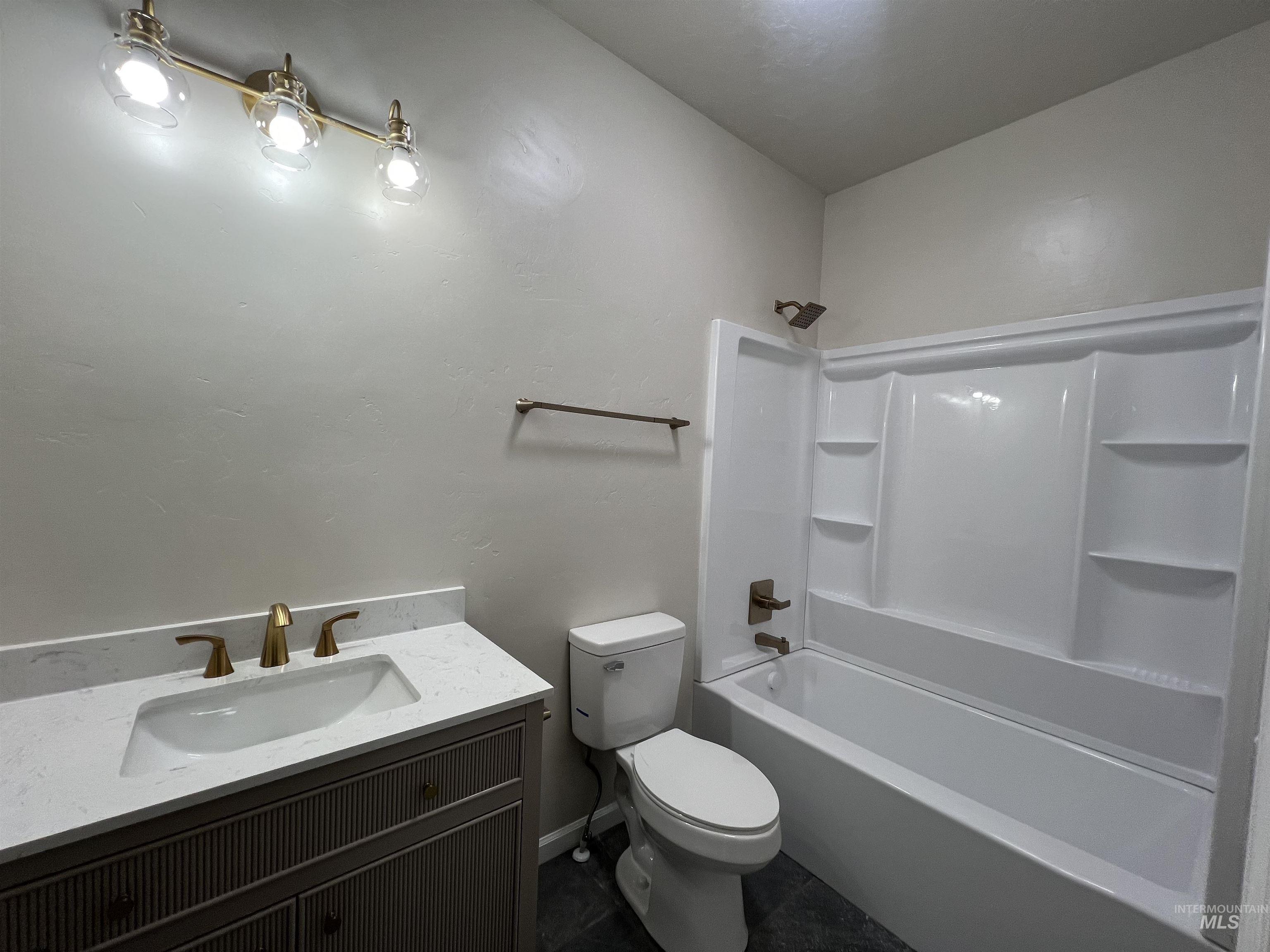 Full bathroom featuring tub / shower combination, vanity, and dark tile patterned floors