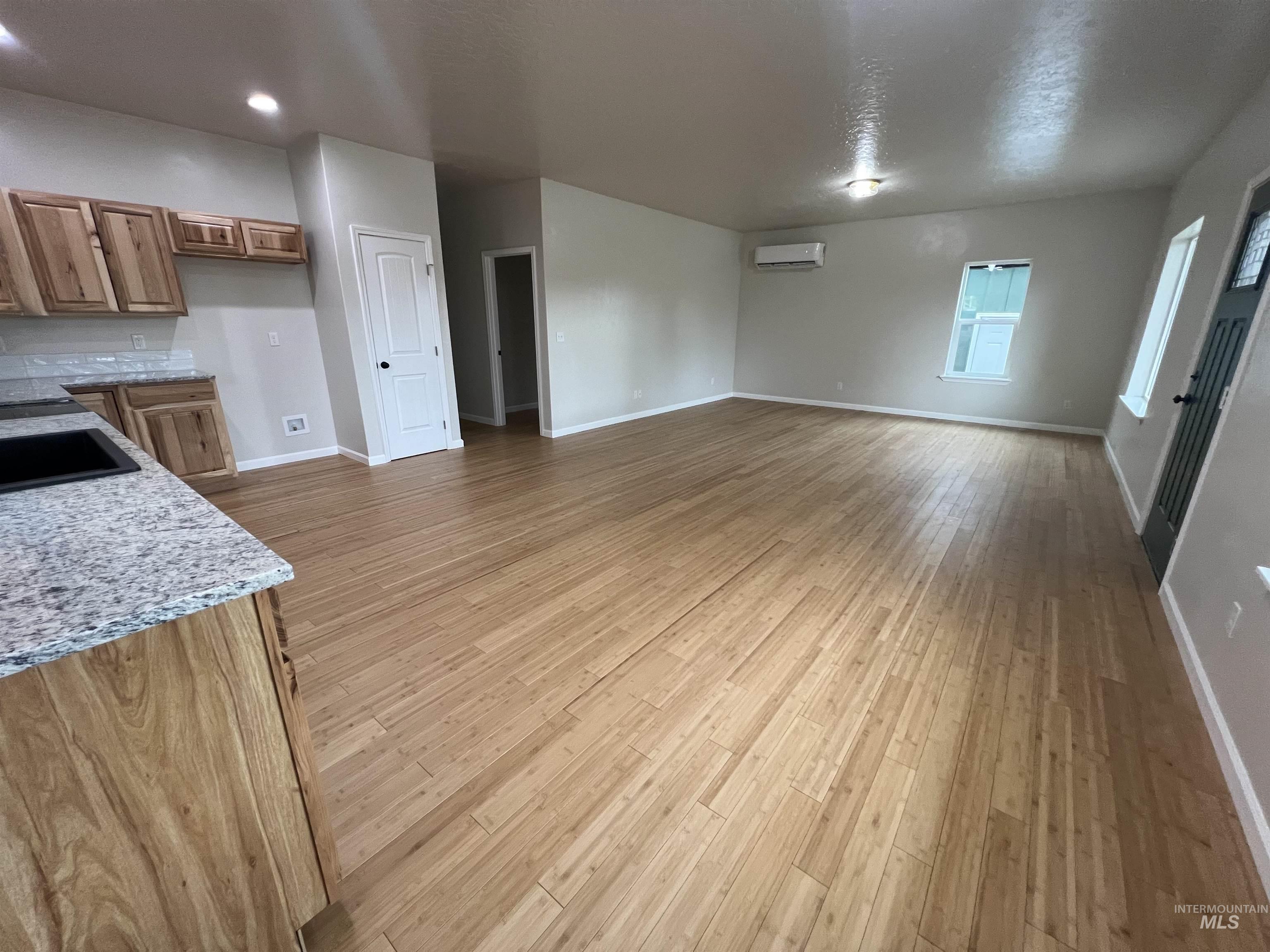 Unfurnished living room with light wood finished floors and a textured ceiling