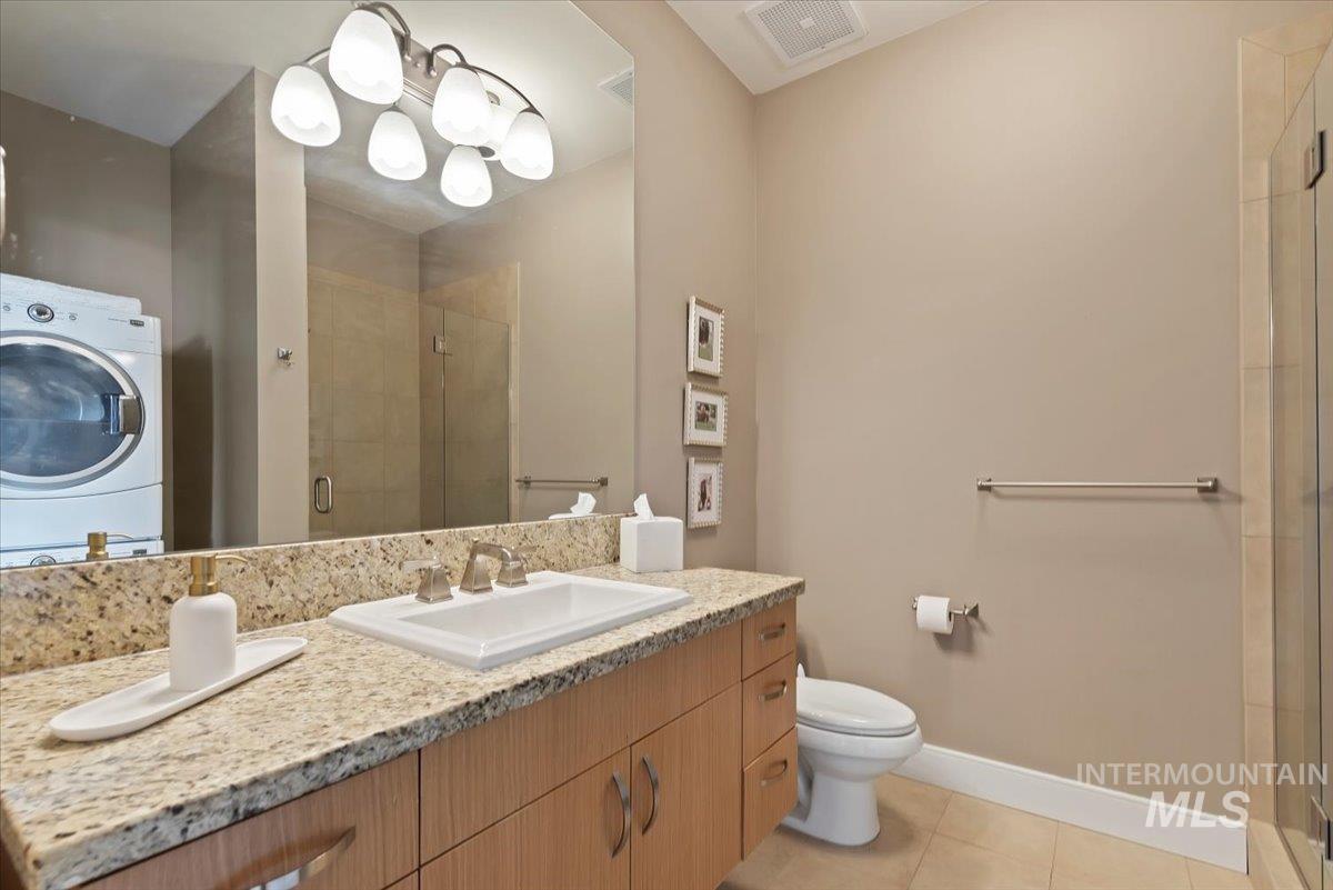 Bathroom featuring washer / clothes dryer, vanity, a shower stall, and light tile patterned flooring